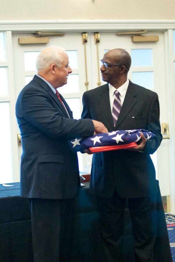 William Jordan receives an American flag from retired Brig. Gen. Leif Hendrickson during his retirement ceremony March 25 at The Clubs of Quantico aboard Marine Corps Base Quantico. The Jacksonville, North Carolina native retired March 24 after 55 years at the Mainside Central Barbershop.