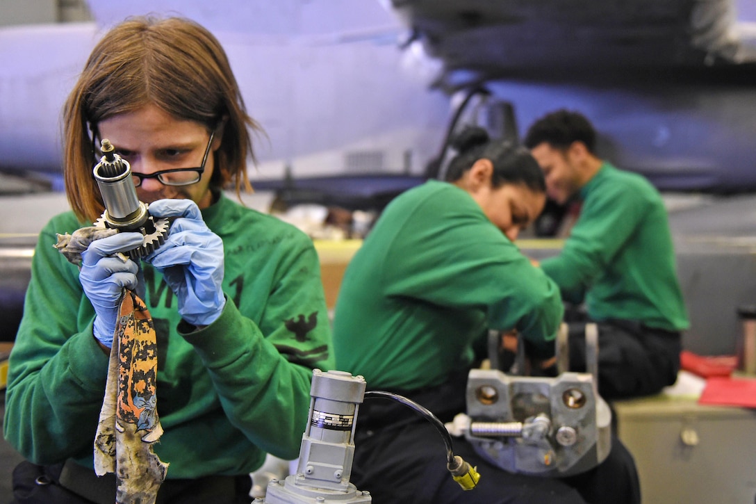 Navy Petty Officer 2nd Class Kali Clapsaddle, foreground, performs maintenance on a rotor spindle from an MH-60R Seahawk helicopter in the hangar bay of the USS John C. Stennis in the Yellow Sea, March 22, 2016. Clapsaddle is an aviation electrician's mate. The Seahawk is assigned to Helicopter Maritime Strike Squadron 71. Navy photo by Petty Officer 3rd Class David Cox