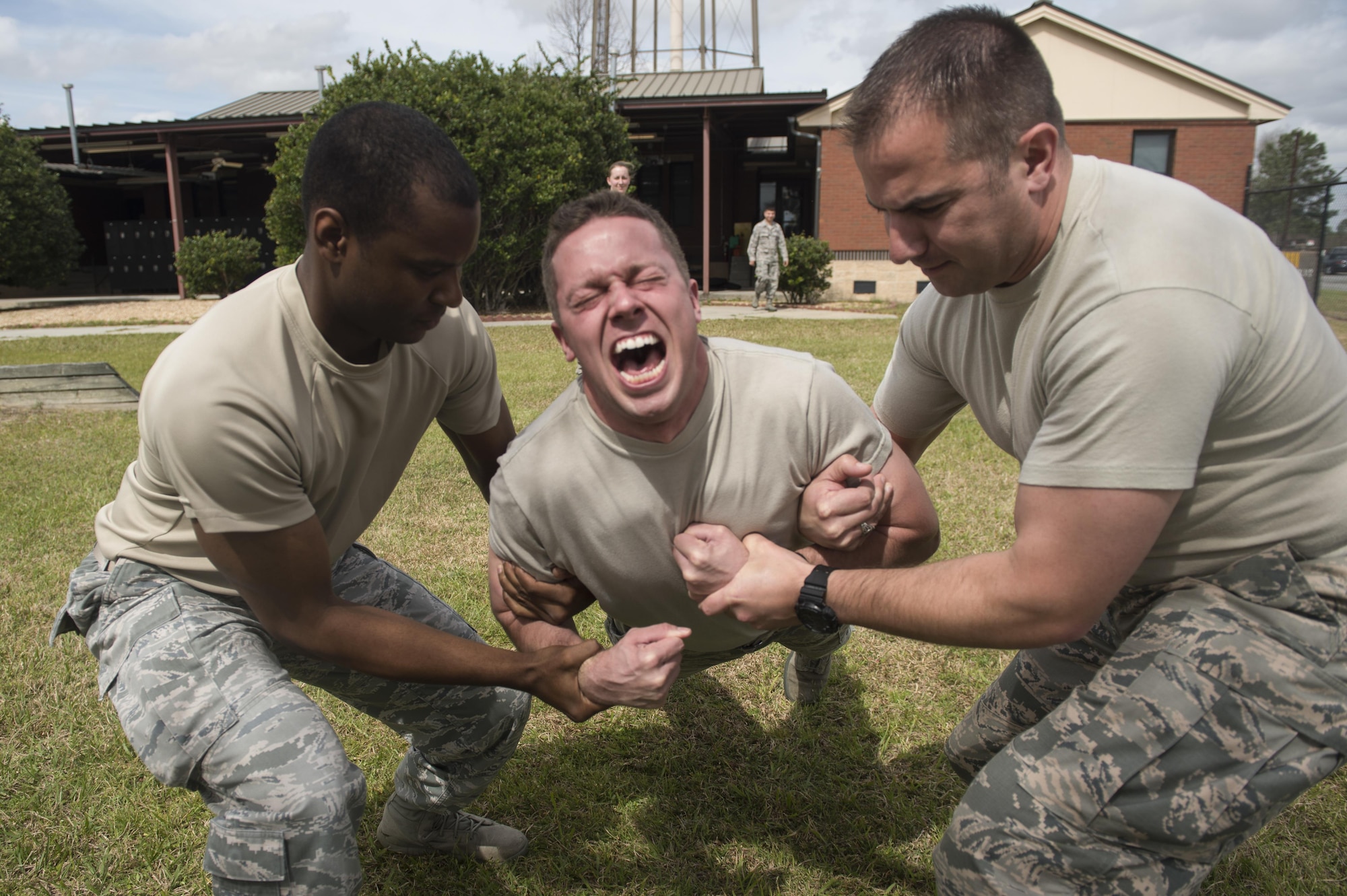 U.S. Air Force Airman Daniel Snider, 23d Wing Public Affairs photojournalist, center, shouts as he is lowered after being shocked by a Taser, March 11, 2016, at Moody Air Force Base, Ga. Snider participated in a Taser course hosted by the 23d Security Forces Squadron. (U.S. Air Force photo by Staff Sgt. Olivia Dominique/Released)