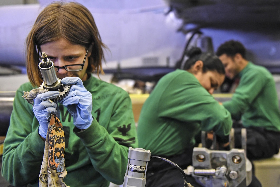 Navy Petty Officer 2nd Class Kali Clapsaddle, foreground, performs maintenance on a rotor spindle from an MH-60R Seahawk helicopter in the hangar bay of the USS John C. Stennis in the Yellow Sea, March 22, 2016. Clapsaddle is an aviation electrician's mate. The Seahawk is assigned to Helicopter Maritime Strike Squadron 71. Navy photo by Petty Officer 3rd Class David Cox