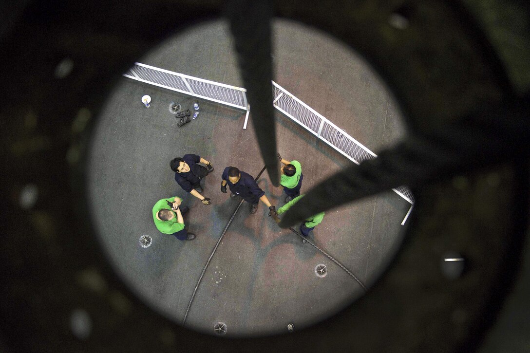 Sailors feed a cable to an engine room from the hangar bay aboard the aircraft carrier USS Dwight D. Eisenhower in the Atlantic Ocean, March 29, 2016. The aircraft carrier is conducting a Composite Training Unit Exercise to prepare for a future deployment. Navy photo by Seaman Nathan Beard