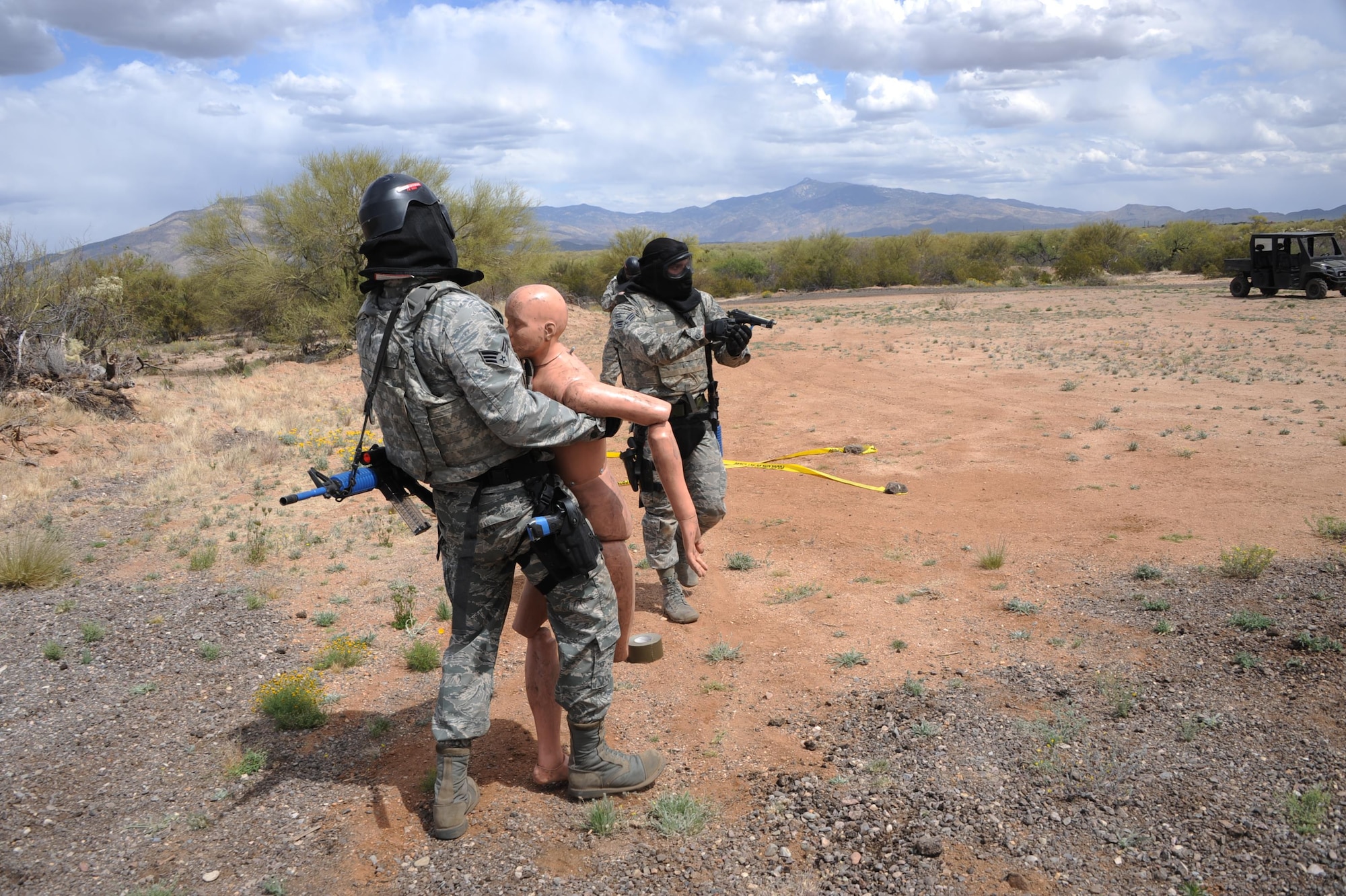 U.S. Air Force Senior Airman Anthony Fernandez, 355th Communications Squadron network technician, provides cover for Senior Airman Mark Lindsay, 355th CS network technician, who is carrying a simulated hostage to safety during the Comprehensive Airman Fitness Month Defender Challenge held by the 355th Security Forces Squadron at Davis-Monthan Air Force Base, March 31, 2016. The challenge simulated a hostage recovery scenario using non-lethal training ammunition to replicate armed combat between opposing forces. (U.S. Air Force photo by Airman Nathan H. Barbour/Released)