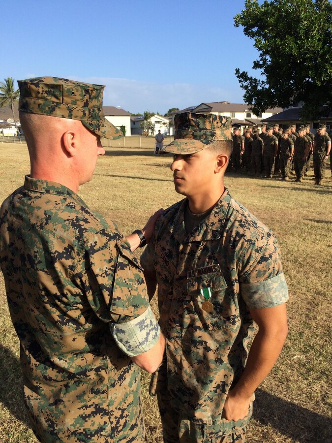 Cpl. Lester Cano shakes the hand of Col. Carl Cooper after being awarded the Navy and Marine Corps Commendation Medal for saving a U.S. Army parachutist that landed in the ocean and was trapped by coral and his own parachute.  Cano is a native of Indianapolis, Indiana
Cpl. Justin Fugate was awarded the same medal moments after.  Cano and Fugate worked as a team on the rescue.
The Marines are assigned to Headquarters Company, 3d Marine Regiment and were awarded by the regimental commanding officer, March 30, on Marine Corps Base Hawaii. On Dec. 15, 2015 a U.S. soldier was blown off course from his drop zone by high winds and parachuted into the Pacific Ocean north of the Mokapu Peninsula that forms Marine Corps Base Hawaii on the island of Oahu. Fugate and Cano were running through the area during their Corporal's Course small unit leader evaluation. They noticed people pointing towards the water and then saw the parachutist. They worked together to develop a rescue plan. Cano improvised a safety line and swam 100 meters out to establish himself as the anchoring relay halfway between the trapped soldier and shore. Meanwhile, Fugate and a lifeguard spent the next hour swimming to reach the soldier where they then freed him from the entangled cordage and retrieved him to the shore. Once ashore, Cano rendered first aid and Fugate assisted until emergency medical services arrived.