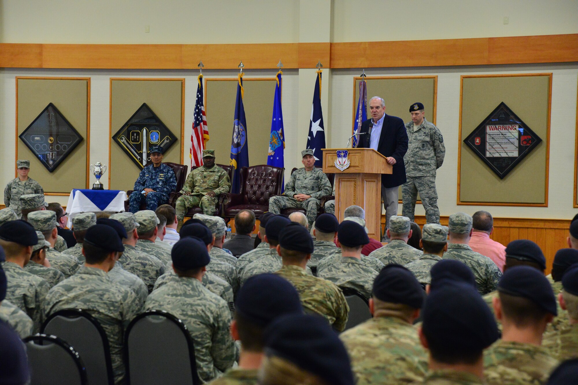 Mr. David G. Brown, Strategic Command Consultation (SCC) Committee member (standing, second from right), provides remarks during an award ceremony honoring the 341st Missile Wing at Malmstrom Air Force Base, Mont., March 30, 2016. During the ceremony, Brown and U.S. Navy Adm. Cecil D. Haney, U.S. Strategic Command (USSTRATCOM) commander (seated left), presented the 2015 Omaha Trophy, ICBM category, to U.S. Air Force Col. John T. Wilcox II, 341st Missile Wing commander (seated right) and Team Malmstrom, in recognition of the wing's contributions to USSTRATCOM's global strategic missions. The Omaha Trophy, which dates back to the U.S. Air Force's Strategic Air Command, was originally created by the SCC in 1971. At the time, a single trophy was presented annually as a token of appreciation to USSTRATCOM's best wing. Since then, the tradition has evolved to unit-level awards that recognize the command's premier intercontinental ballistic missile (ICBM) wing, ballistic missile submarine, strategic bomber wing and global operations (space/cyberspace) unit. This year, a new category was added to include the combatant command's top strategic aircraft wing. (U.S. Air Force photo by Airman Daniel Brosam)