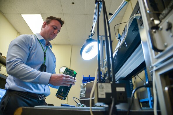 Engineer Phillip Smith, with the Air Force Lifecycle Management Center's Aerospace Dominance Enabler Division, works on a circuit card for the P5 Combat Training System pod. The pod is used to track an aircraft's movements in flight as well as deploy simulated weapons during combat training for pilots. (Air Force photo by R. Nial Bradshaw) 