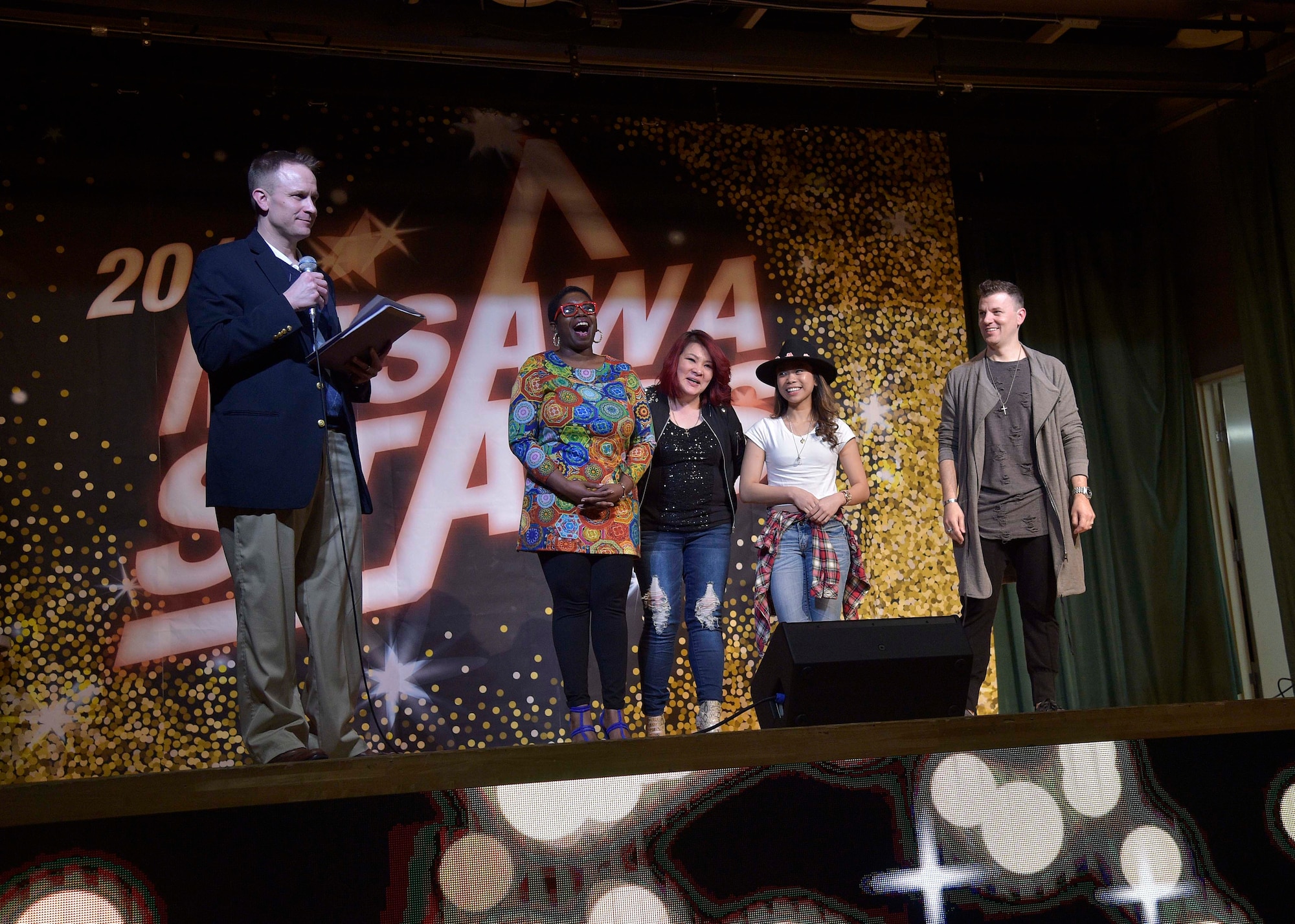 Matthew Jobe, the community service flight chief with the 35th Force Support Squadron, announces the contestants moving on to the next round during Misawa Stars at Misawa Air Base, Japan, March 25, 2016. Each week three contestants may be eliminated. The finale, which is May 6, will grant the top three winners with cash prizes and 35th FSS gift cards.  (U.S. Air Force photo by Senior Airman Deana Heitzman)