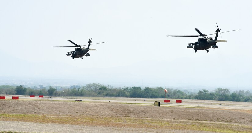 Two U.S. Army UH-60 Black Hawks depart Soto Cano Air Base in support of firefighting efforts on the North coast of Honduras, Mar. 31, 2016, after Juan Orlando Hernandez, President of Honduras, sent a request for support to the U.S. Ambassador in Honduras. The helicopters, assigned to the 1-228th Aviation Regiment, maintain Bambi Bucket and hoist capabilities, allowing them to support Honduran fire response forces fighting fires like those affecting the Jeanette Kawas National Park in northern Honduras. (U.S. Army photo by Martin Chahin/Released)