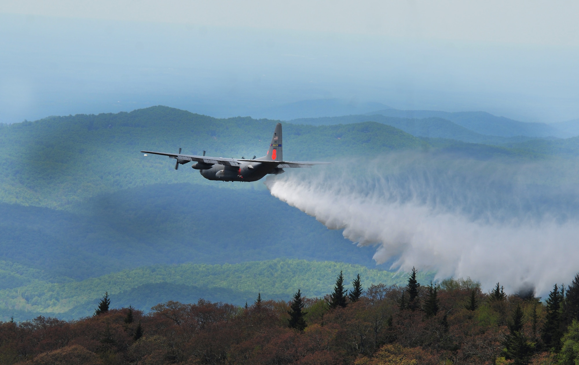 A C-130 Hercules aircraft (MAFFS 8) assigned to the 145th Airlift Wing, North Carolina Air National Guard, drops water in the Pisgah National Forest during Modular Airborne Firefighting System (MAFFS) training May 5, 2012. Annual training is conducted to maintain currency and upgrade qualifications for pilots, aircrew and ground crews in preparation for the fire season. Military C-130s equipped with MAFFS systems can drop up to 3,000 gallons of water on wildfires. ( Air National Guard photo by Master Sgt. Patricia F. Moran/Released)