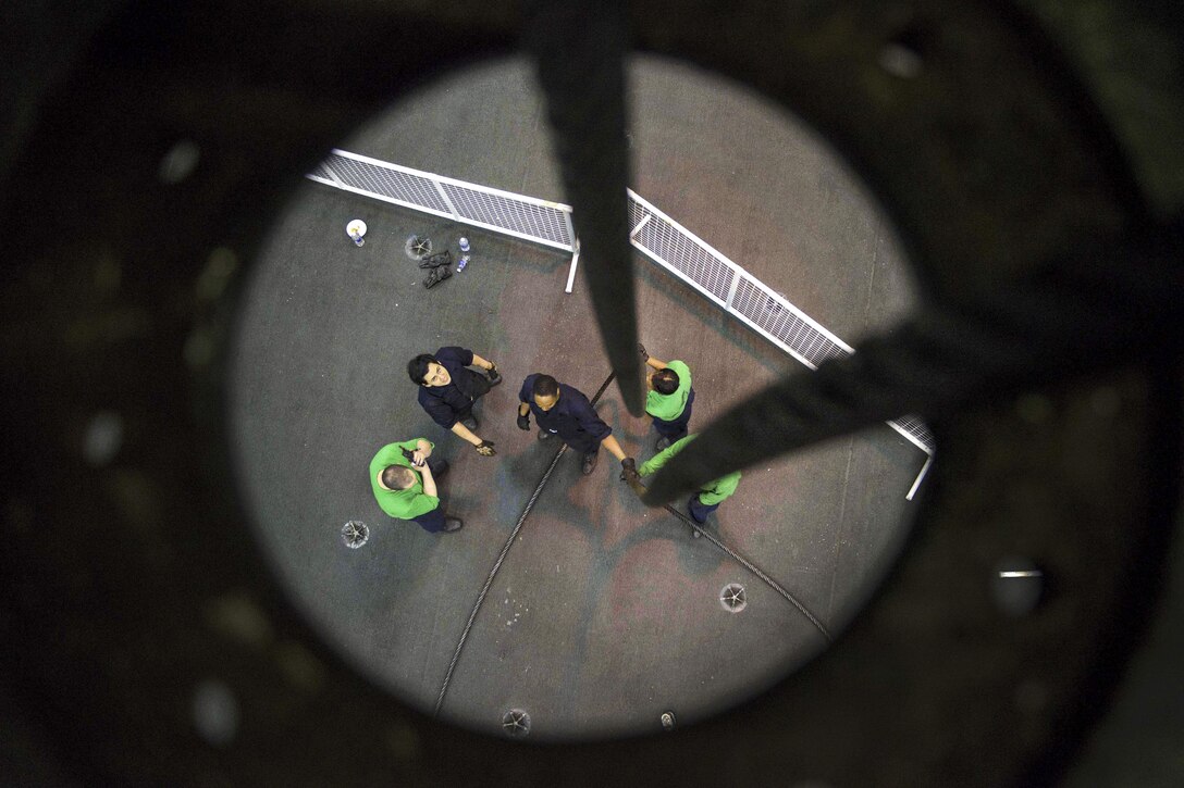 Sailors feed a cable to an engine room from the hangar bay aboard the aircraft carrier USS Dwight D. Eisenhower in the Atlantic Ocean, March 29, 2016. The aircraft carrier is conducting a Composite Training Unit Exercise with the Eisenhower Carrier Strike Group to prepare for a future deployment. Navy photo by Seaman Nathan Beard