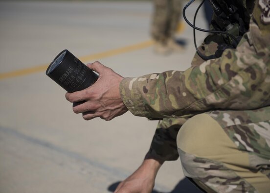 A pararescueman from the 83rd Expeditionary Rescue Squadron readies a smoke canister to mark placement for the team preparing to jump from a C-130J Super Hercules during a mission rehersal at Bagram Airfield, Afghanistan, April 28, 2016. This mission rehearsal is key to ensure pararescuemen are ready for real world missions throughout Afghanistan. (U.S. Air Force photo by Technical Sgt. Robert Cloys)