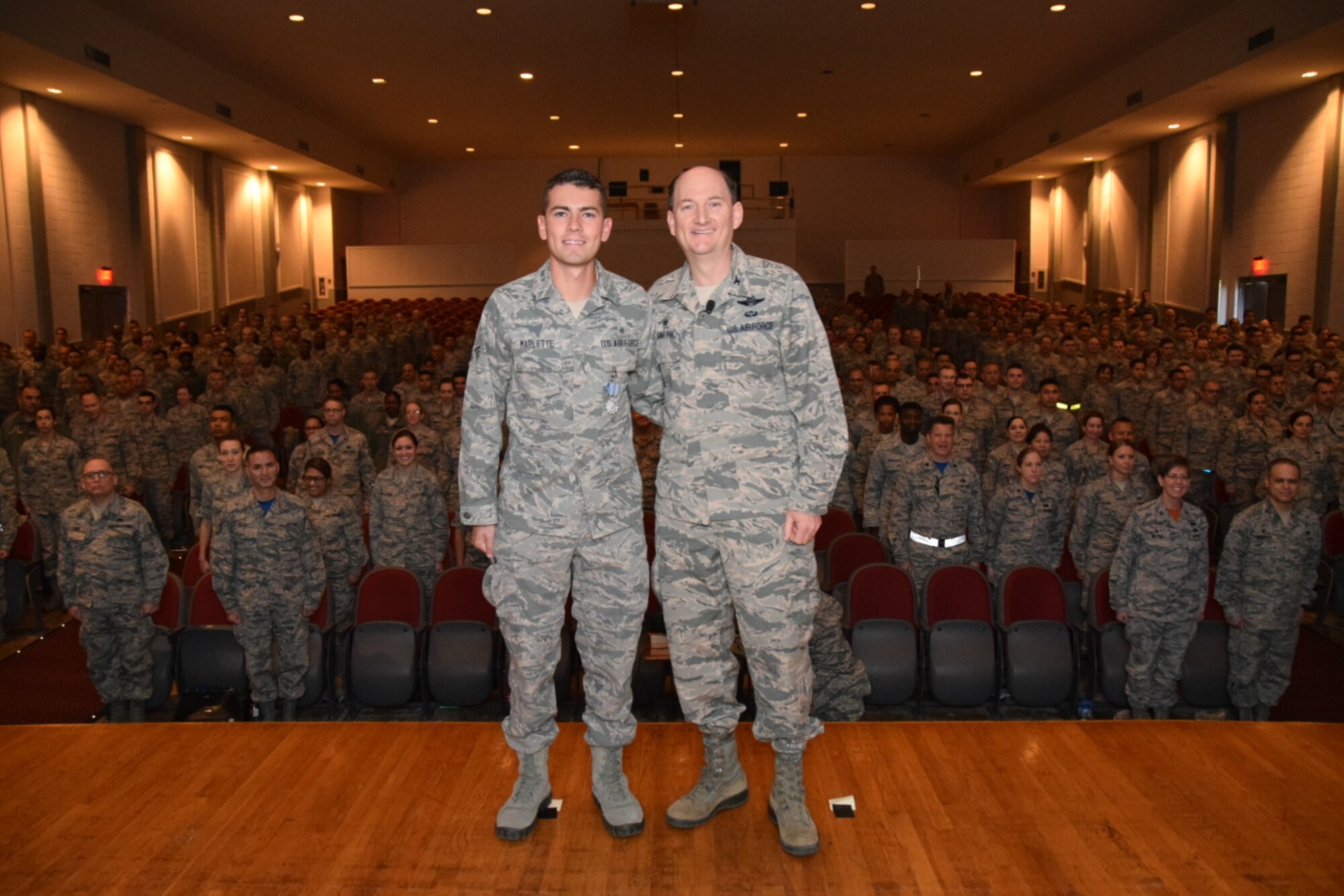 Col. Thomas K. Smith Jr., 433rd Airlift Wing commander, right, congratulates Senior Airman Brandon Marlette, of the 433rd Medical Squadron, after presenting him the Air Force Achievement Medal during the 433rd AW commander's call April 3 at the Bob Hope Theater, Joint Base San Antonio-Lackland. (U.S. Air Force photo by Tech. Sgt. Carlos J. Trevino)