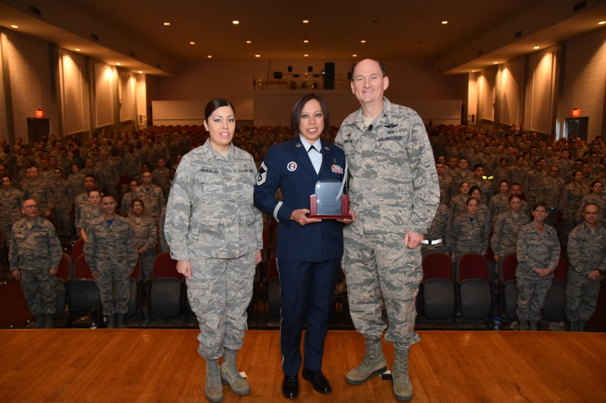 Col. Thomas K. Smith Jr., 433rd Airlift Wing commander, right, presents Senior Master Sgt. Christina Bantin, center, and Tech. Sgt. Janice Penuelaz, both with the 433rd Aerospace Medicine Squadron, with the 2015 Air Force Reserve Command Outstanding Base-Level Drug Demand Reduction Program Office (Large-Size Base Category) during the 433rd AW commander's call April 3, 2016 at the Bob Hope Theater, Joint Base San Antonio-Lackland. (U.S. Air Force photo by Tech. Sgt. Carlos J. Trevino)