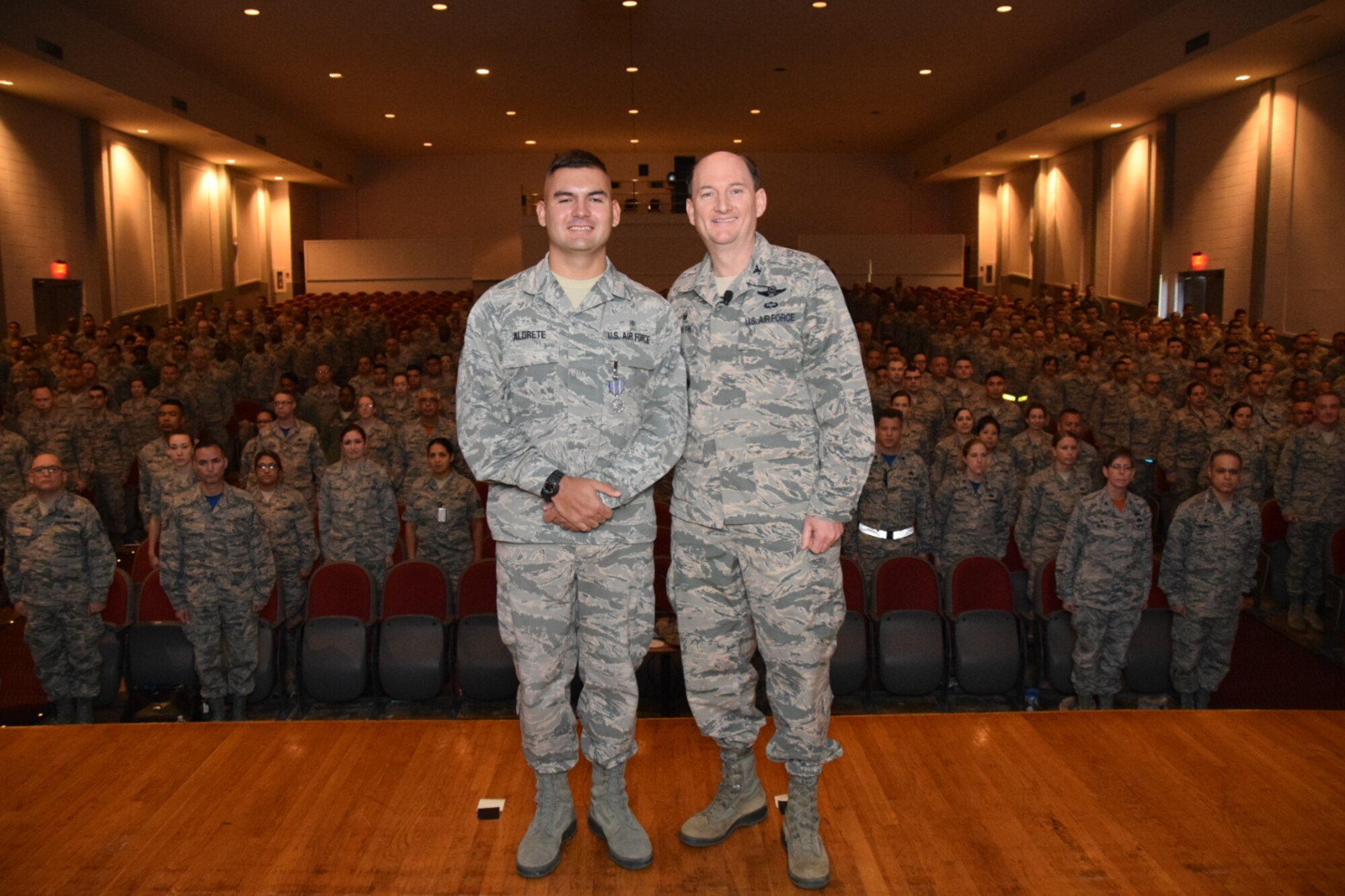 Col. Thomas K. Smith Jr., 433rd Airlift Wing commander, right, congratulates Senior Airman Joe Lopez, of the 433rd Operations Support Squadron, after presenting him the Air Force Achievement Medal during the 433rd AW commander's call April 3, 2016 at the Bob Hope Theater, Joint Base San Antonio-Lackland. (U.S. Air Force photo by Tech. Sgt. Carlos J. Trevino)