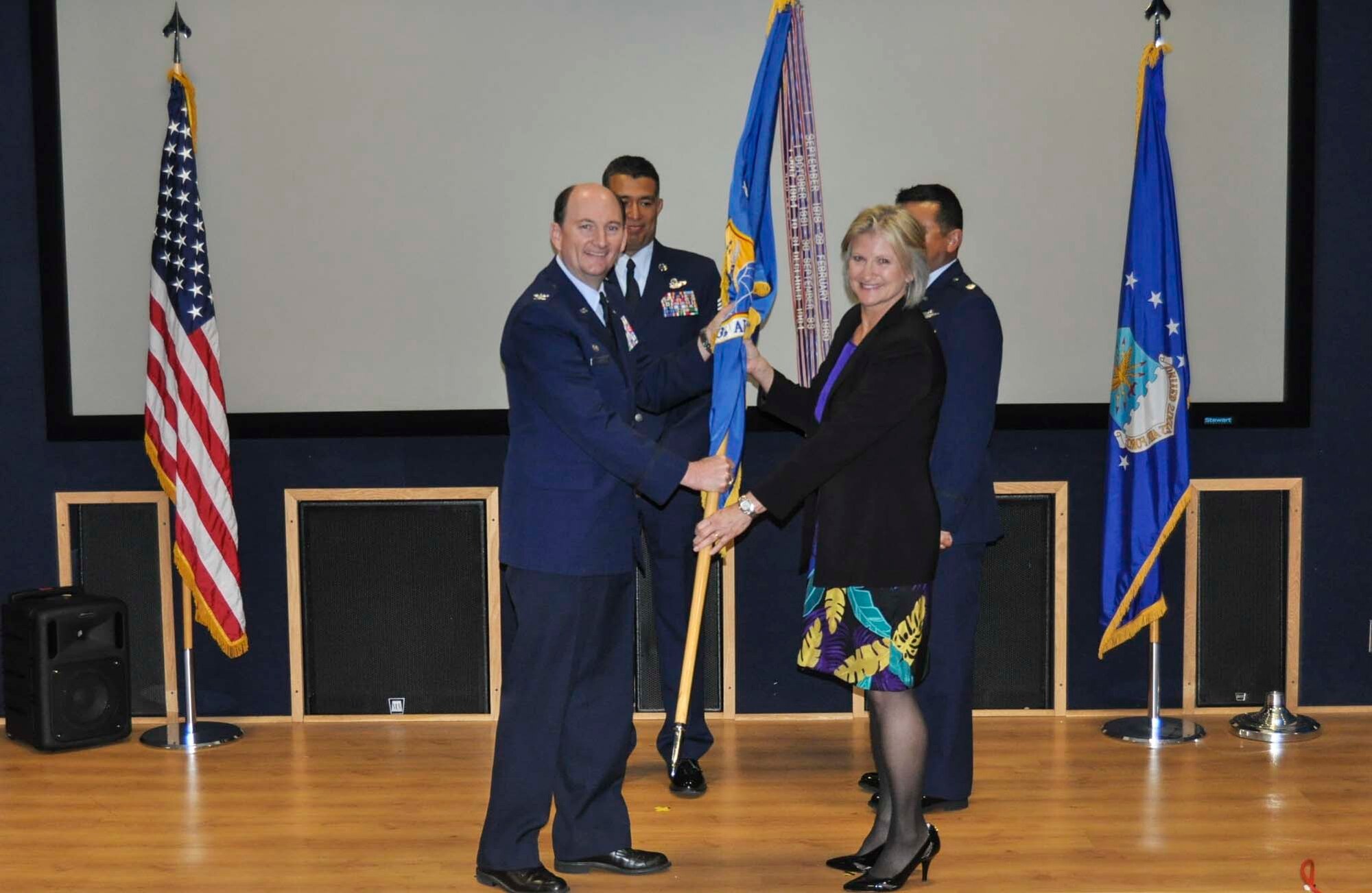 Audrey Magnuson accepts the 433rd Airlift Wing guidon from Col. Thomas K. Smith, Jr., 433rd Airlift Wing commander, during the Honorary Commanders Induction Ceremony April 30, 2016 at Joint Base San Antonio-Lackland. Magnuson is the director of the University of Texas San Antonio University Career Center and will be serving as the 433rd Aeromedical Evacuation Squadron Honorary Commander. (U.S. Air Force photo/Senior Airman Bryan Swink)