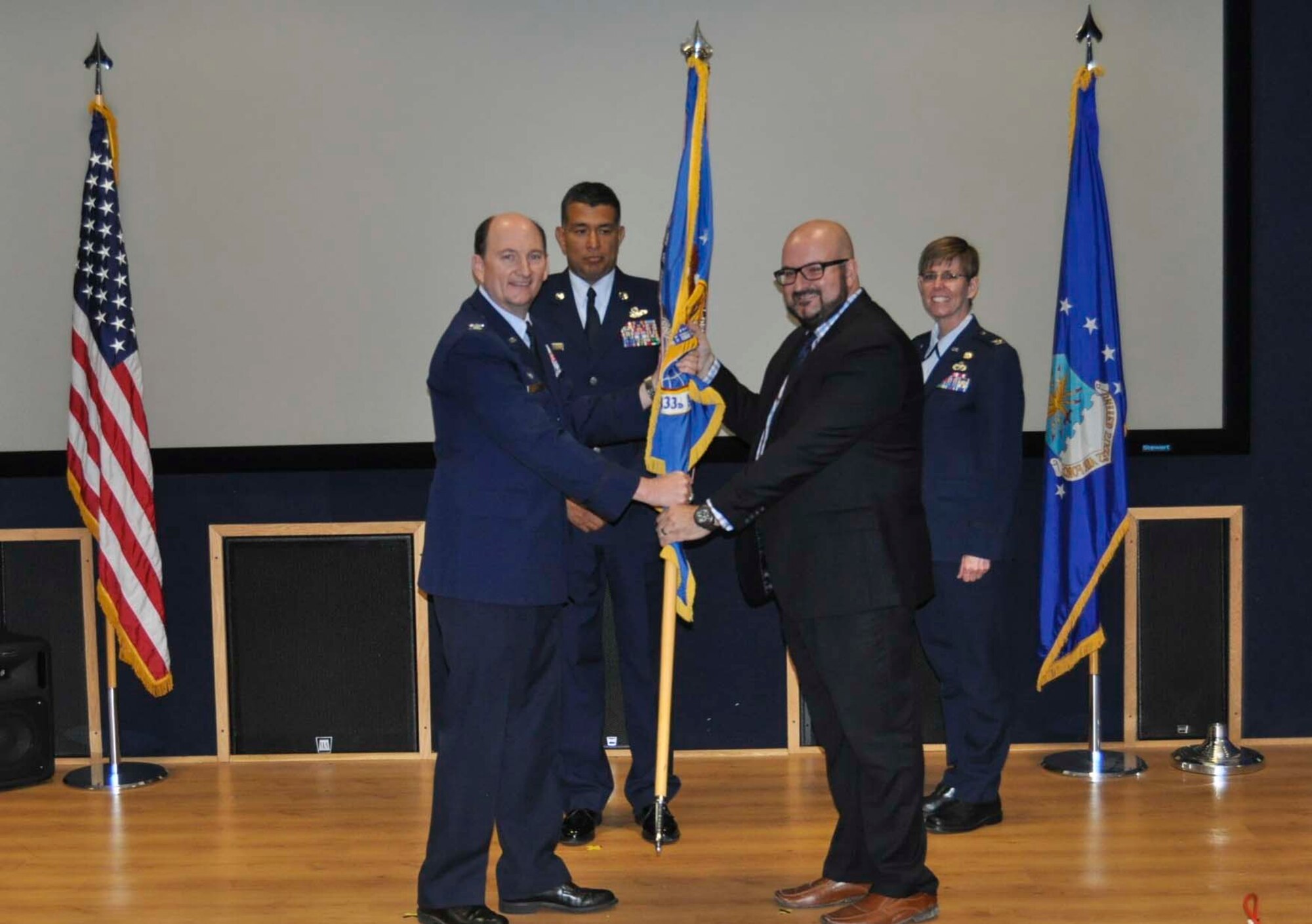 Philippe Place accepts the 433rd Airlift Wing guidon from Col. Thomas K. Smith, Jr., 433rd AW commander, during the Honorary Commanders Induction Ceremony held at Joint Base San Antonio-Lackland April 30, 2016. Place is the general manager of Southerleigh Fine Food and Brewery and will be serving as the 433rd Maintenance Group Honorary Commander. (U.S. Air Force photo/Senior Airman Bryan Swink)