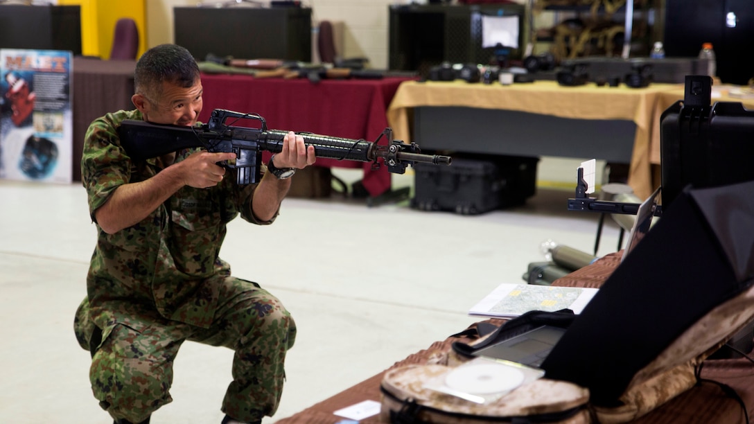 A Japan Ground Self-Defense Force member visiting the annual Training Expo at Camp Hansen, Okinawa, Japan tests out the Instrumental Tactical Evaluation Simulated System on Friday, April 29, 2016. This recently updated system works almost like the popular game, "laser tag," where a laptop traces the marksmanship of the shooter. This training can be recorded and handed back to the unit on a CD to evaluate performance.