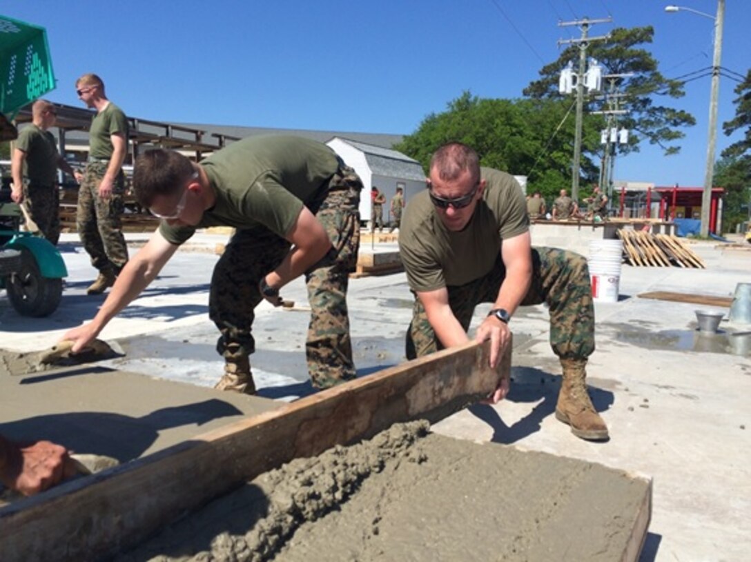 April 26, 2016 Second Lieutenants Troy Searcy and Justin Wilkison, Marines attached to Combat Engineer Officer course 5-16 (CEO 5-16); level out a 4’x8’ concrete pad using a 2”x6” board and a float as part of concrete construction training at Marine Corps Engineer School, Camp Lejeune, N.C. These techniques help to create a more stable concrete pad by removing air pockets from the concrete.