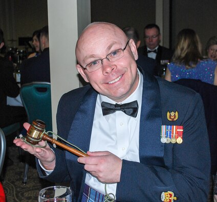 Canadian Warrant Officer Richard Martin takes a moment to show off his newly acquired official mess gavel that Canadian Capt. Stephen Buckley was unable to secure properly as the President of the Mess Committee. The reminder of the night, Buckley had to enforce the mess rules of engagement using a red and blue plastic Fisher Price hammer appropriated from his children’s toy box. (U.S. Air National Guard photo by Capt. Kimberly Burke)