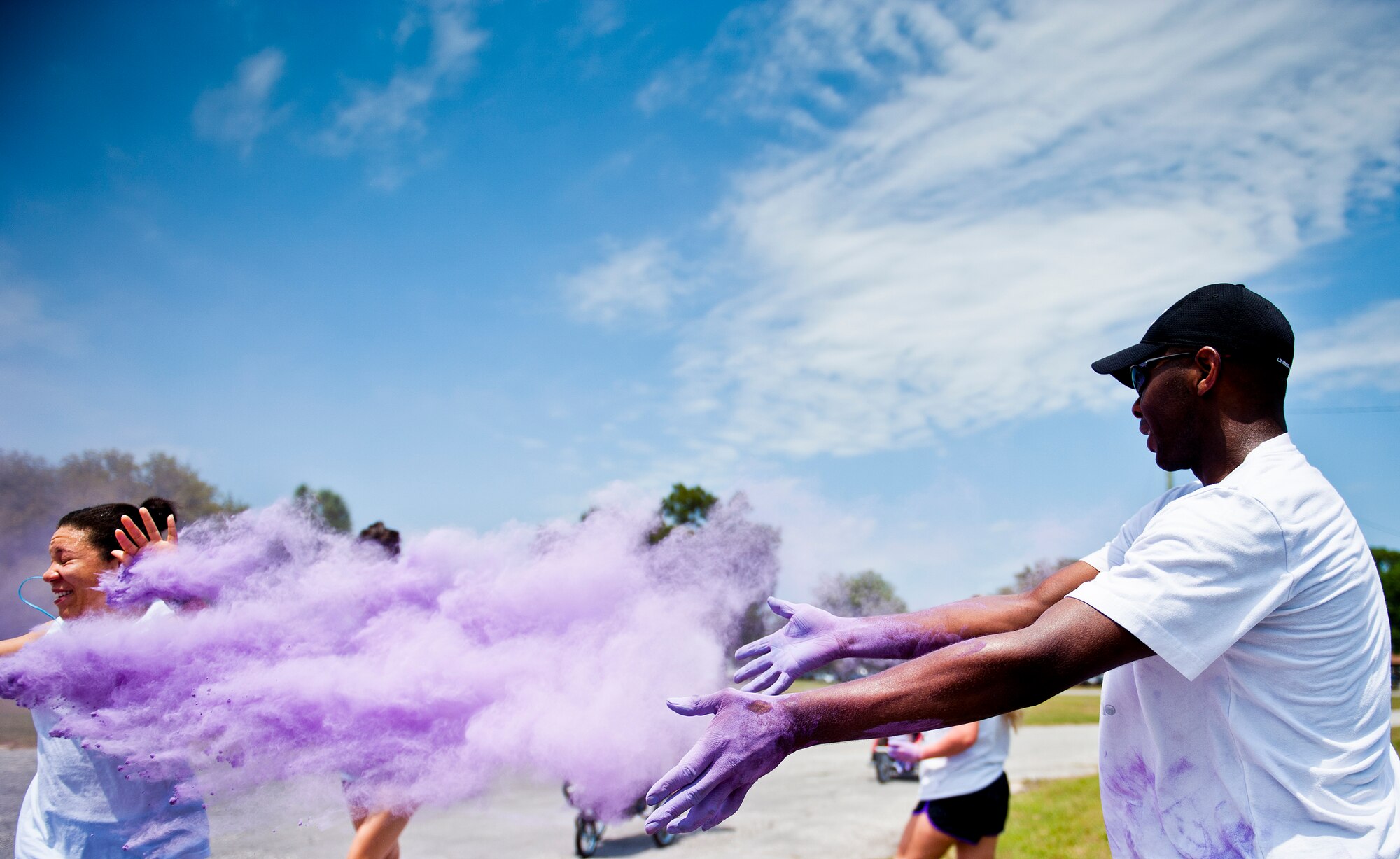 A volunteer showers a runner with a cloud of purple dust at the beginning of the Sexual Assault Prevention and Response Color Run at Eglin Air Force Base, Fla., April 29.  Approximately 300 runners turned out to add a little color to their afternoon workout.  (U.S. Air Force photo/Samuel King Jr.)