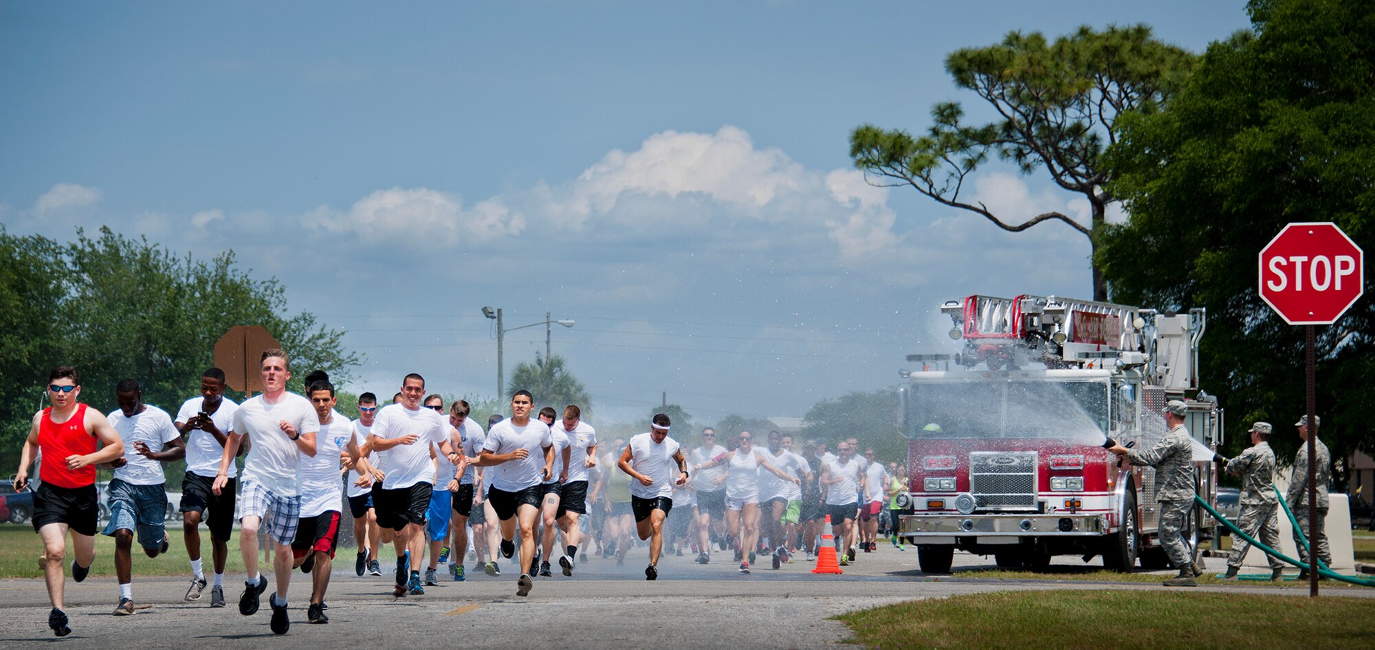 Runners sprint through the shower provided by the base fire department at the beginning of the Sexual Assault Prevention and Response Color Run at Eglin Air Force Base, Fla., April 29.  Approximately 300 runners turned out to add a little color to their afternoon workout.  (U.S. Air Force photo/Samuel King Jr.)