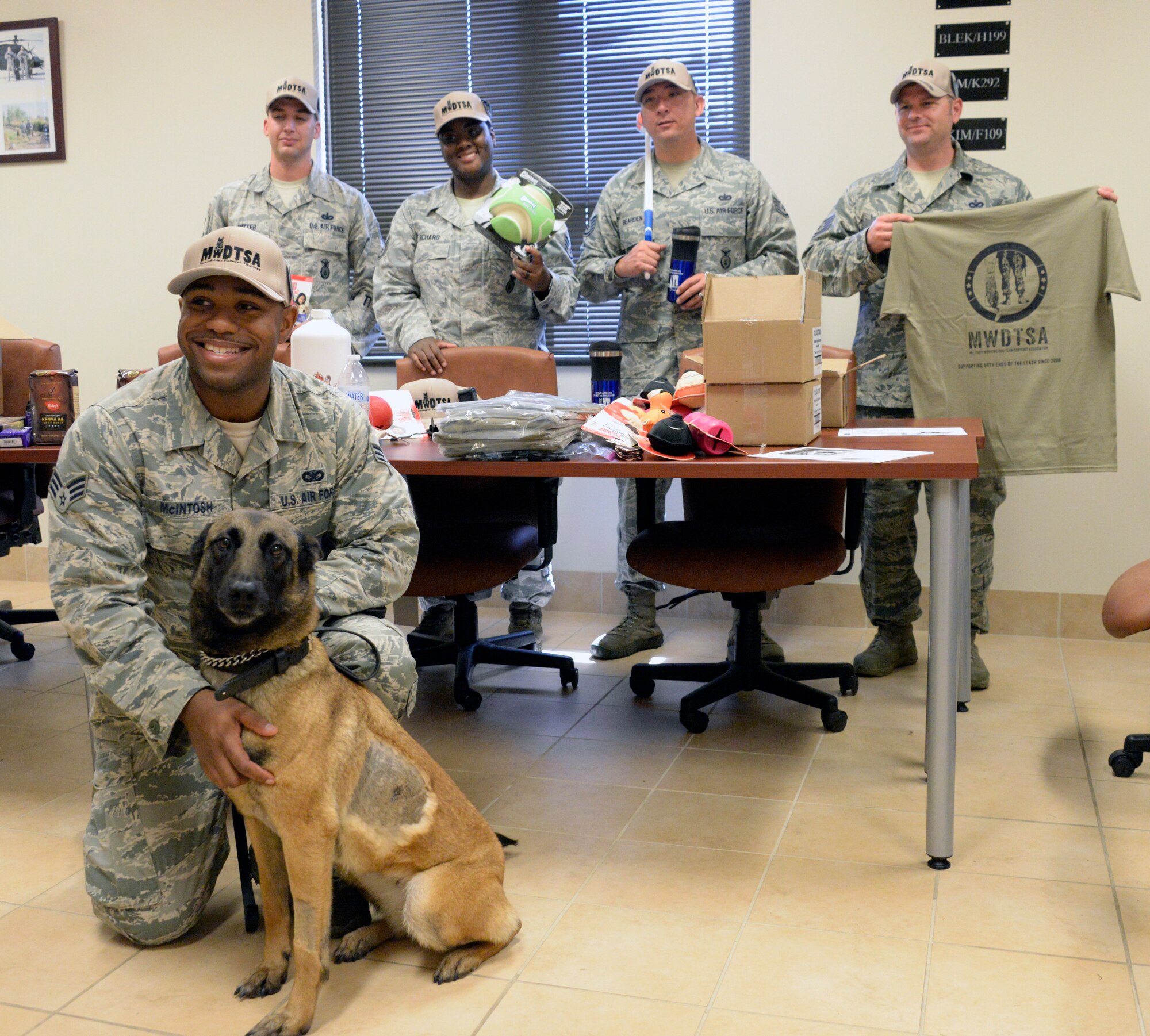 Military Working Dog handlers pose for a photo with the donations they received from the Military Working Dog Team Support Association, April 21, 2016. Coffee, hats, shirts and coffee mugs were donated to the handlers, while the MWDs received food, toys and Air Force themed bandanas. (U.S. Air Force photo/Senior Airman Tammie Ramsouer)