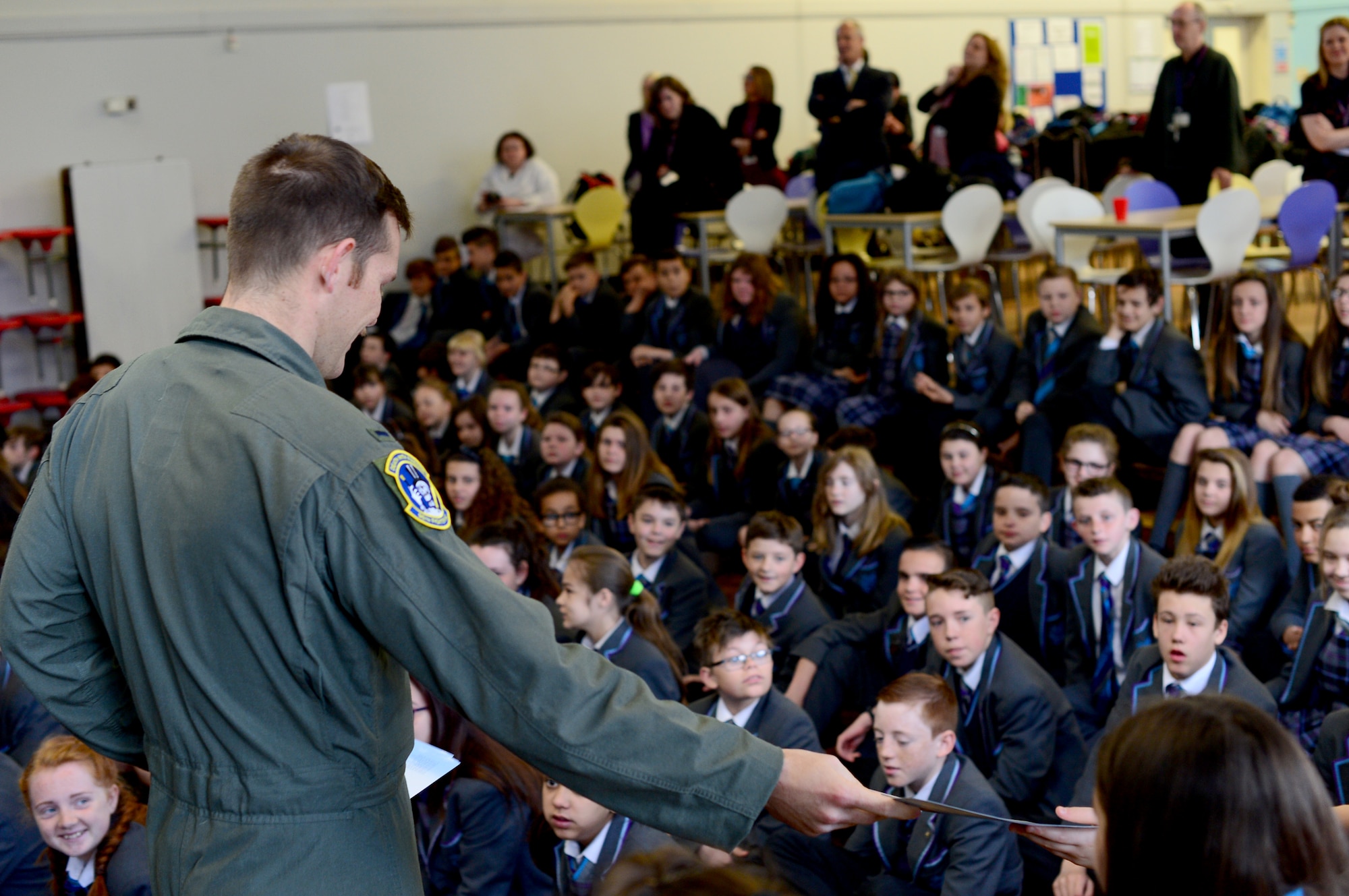 U.S. Air Force 1st. Lt. Connor Ference, 95th Fighter Squadron F-22 Raptor pilot, distributes posters to British students at IES Breckland in Brandon, England, April 26. The Airmen from the 95th FS located at Tyndall Air Force Base, Fla., who are temporarily deployed to Royal Air Force Lakenheath, England, visited children of the local community to educate them about the U.S. Air Force mission and their respective career fields. (U.S. Air Force photo/Senior Airman Erin Trower)