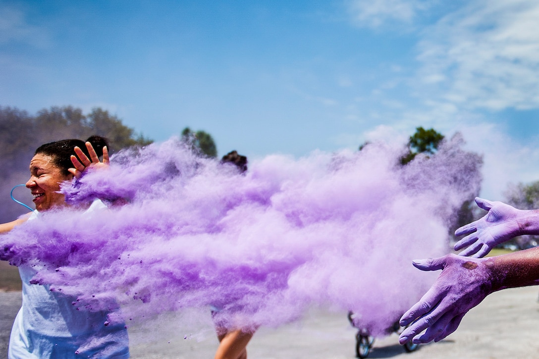 A volunteer showers a runner with a cloud of purple dust at the beginning of the Sexual Assault Prevention and Response Color Run at Eglin Air Force Base, Fla., April 29, 2016. About 300 runners participated in the event. Air Force photo by Samuel King Jr.