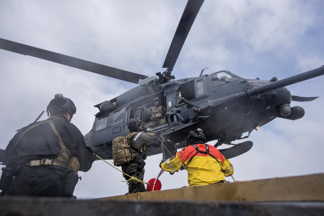 An airman communicates with a crew chief in an HH-60G Pave Hawk helicopter participating in a simulated casualty evacuation training exercise off the coast of Homer, Alaska, April 27, 2016. Alaska National Guard photo by Air Force Staff Sgt. Edward Eagerton