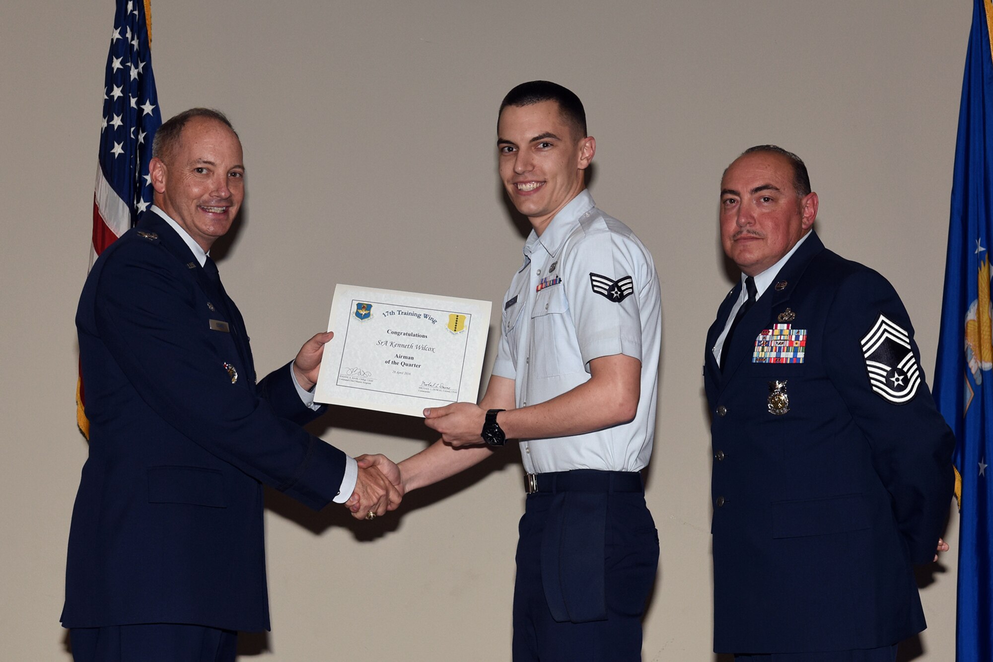 U.S. Air Force Col. Michael L. Downs, 17th Training Wing Commander, and Chief Master Sgt. Jesus Longoria Jr., 312th Training Squadron superintendent, present the Airman of the Quarter award to Senior Airman Kenneth Wilcox, 17th Communications Squadron, during the wing quarterly awards ceremony at the Event Center on Goodfellow Air Force Base, Texas, April 29, 2016. (U.S. Air Force photo by Staff Sgt. Laura R. McFarlane/Released)