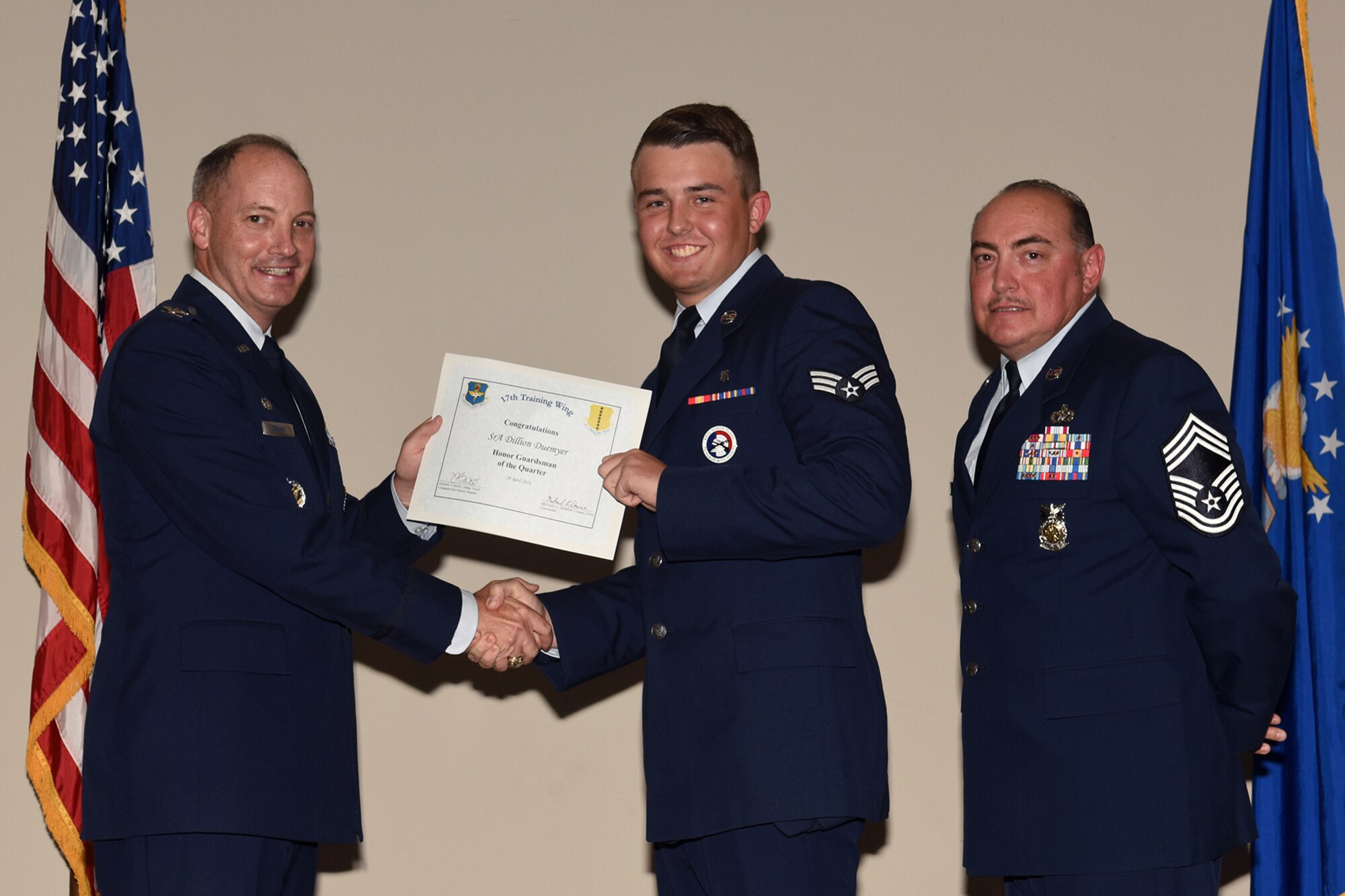 U.S. Air Force Col. Michael L. Downs, 17th Training Wing Commander, and Chief Master Sgt. Jesus Longoria Jr., 312th Training Squadron superintendent, present the Honor Guard of the Quarter award to Senior Airman Dillon Duermyer, 17th Medical Support Squadron, during the wing quarterly awards ceremony at the Event Center on Goodfellow Air Force Base, Texas, April 29, 2016. (U.S. Air Force photo by Staff Sgt. Laura R. McFarlane/Released)