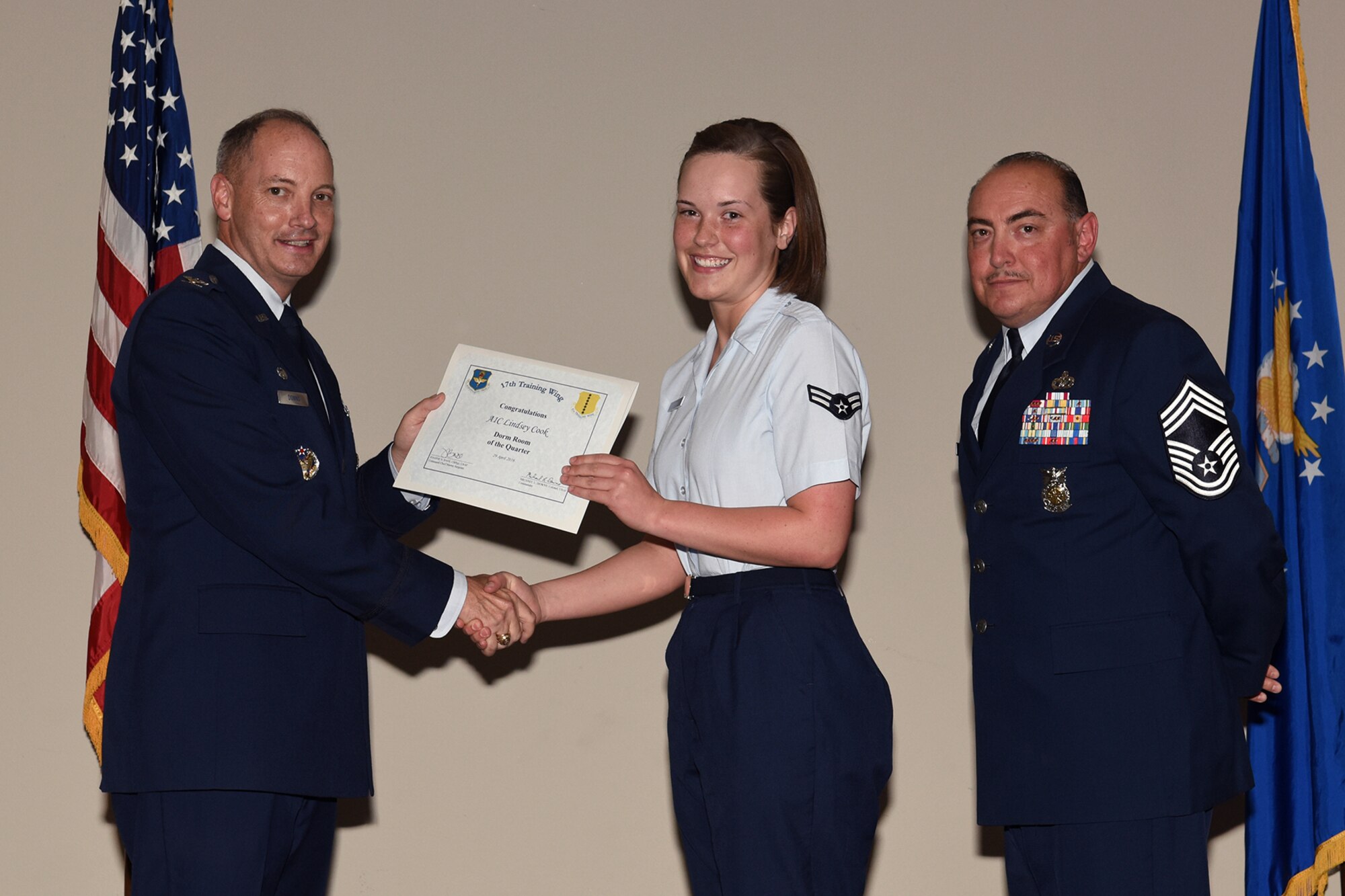 U.S. Air Force Col. Michael L. Downs, 17th Training Wing Commander, and Chief Master Sgt. Jesus Longoria Jr., 312th Training Squadron superintendent, present the 17th Training Wing Dorm Room of the Quarter award to Airman 1st Class Lindsey Cook, 17th Communications Squadron, during the wing quarterly awards ceremony at the Event Center on Goodfellow Air Force Base, Texas, April 29, 2016. (U.S. Air Force photo by Staff Sgt. Laura R. McFarlane/Released)