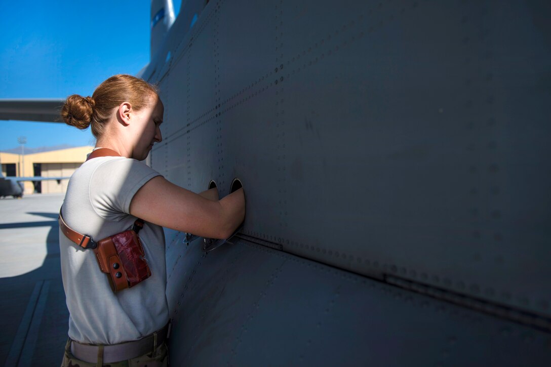 Air Force Senior Airman Jessica Jones locks the landing gear cover into place during a preflight inspection of a C-130J Super Hercules aircraft at Bagram Airfield, Afghanistan, April 29, 2016. Air Force photo by Senior Airman Justyn M. Freeman