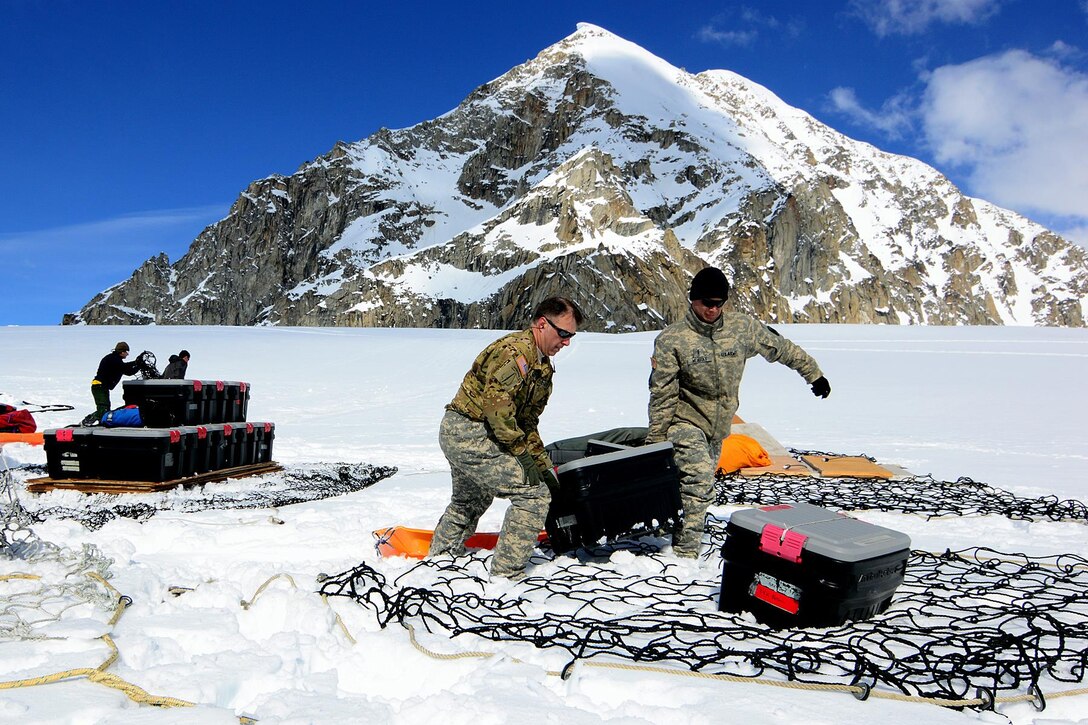 Army Chief Warrant Officers 3 Kirk Donovan, left, and Gene Murray offload equipment and supplies from a CH-47F Chinook helicopter after landing on Kahiltna Glacier, Alaska, April 24, 2016. Donovan and Murray are pilots assigned to Company B, 1st Battalion, 52nd Aviation Regiment. Army photo by John Pennell