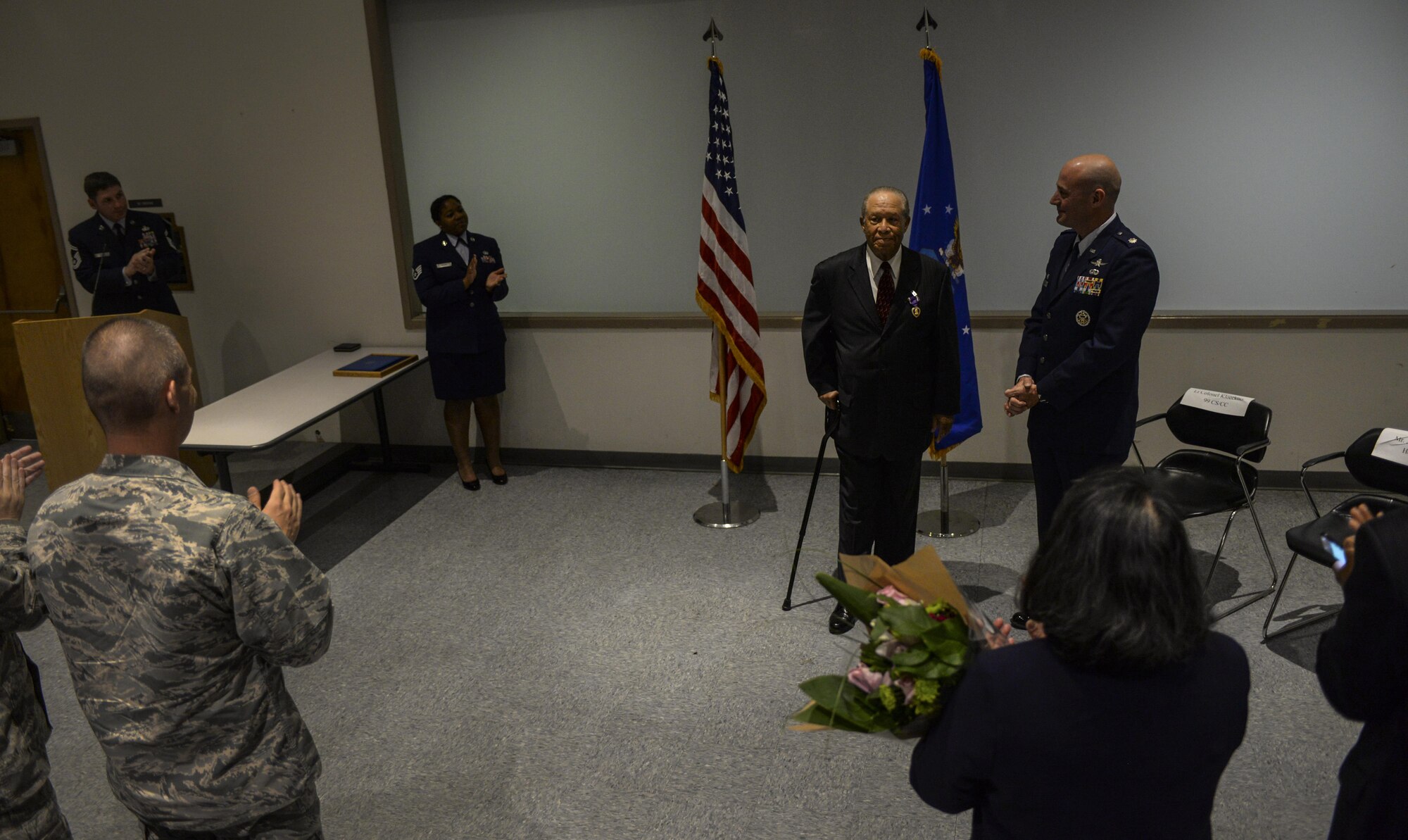 Retired Airman 1st Class Julius Farrar receives a standing ovation after giving a speech during his Purple Heart ceremony at Nellis Air Force Base, Nev., April 28, 2016. The Purple Heart is awarded to personnel who receive wounds in action against an armed enemy against the United States during periods of war, armed conflict, or lost their lives as a result of hostile foreign forces. (U.S. Air Force photo by Airman 1st Class Kevin Tanenbaum)