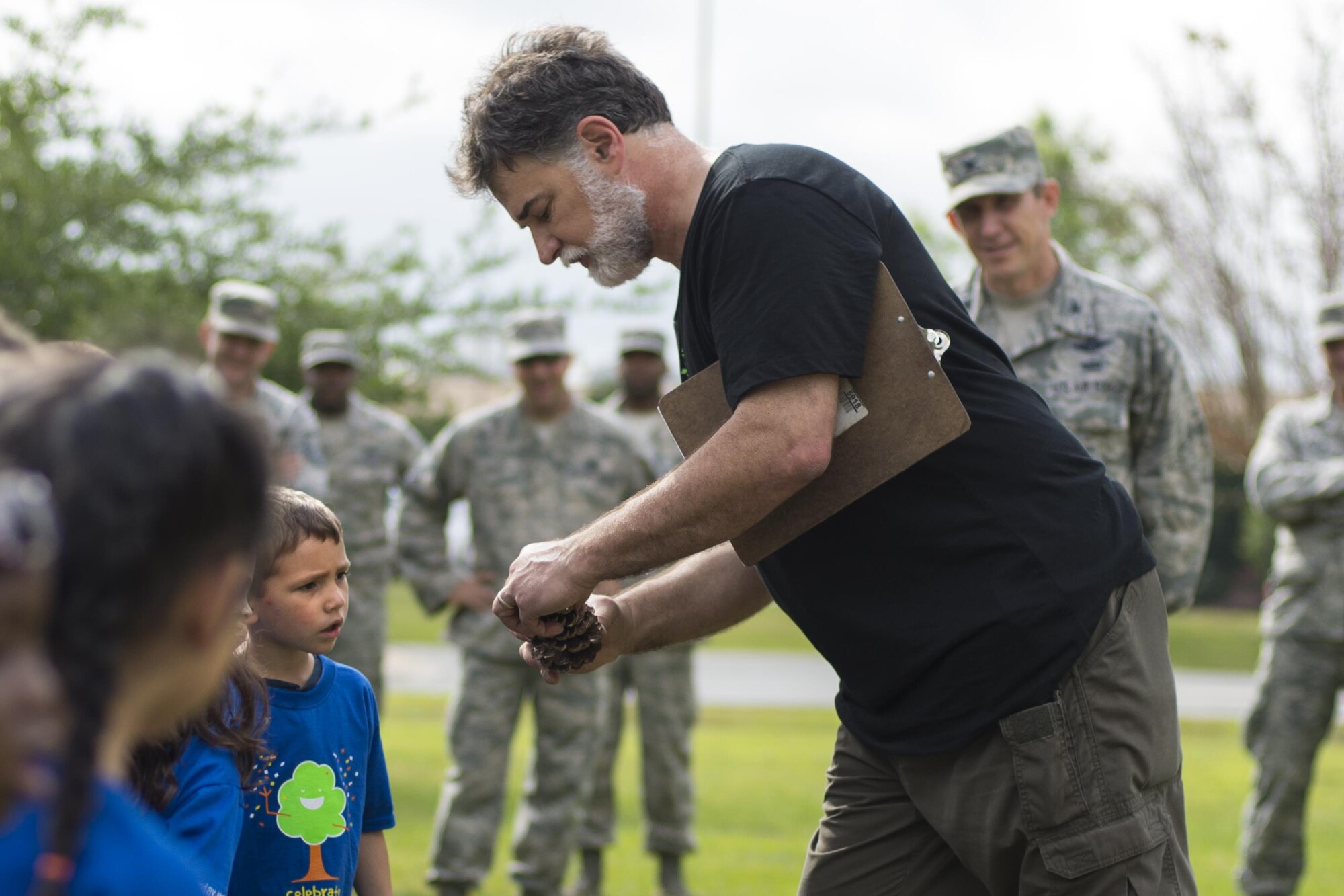 John Crain, 23d Civil Engineer Squadron forester, shows children from the Child Development Center II a pinecone during an Arbor Day ceremony, April 28, 2016, at Moody Air Force Base, Ga. Crain taught children that trees contribute to all sorts of household items, to include toothpaste. (U.S. Air Force photo by Airman Daniel Snider/Released)