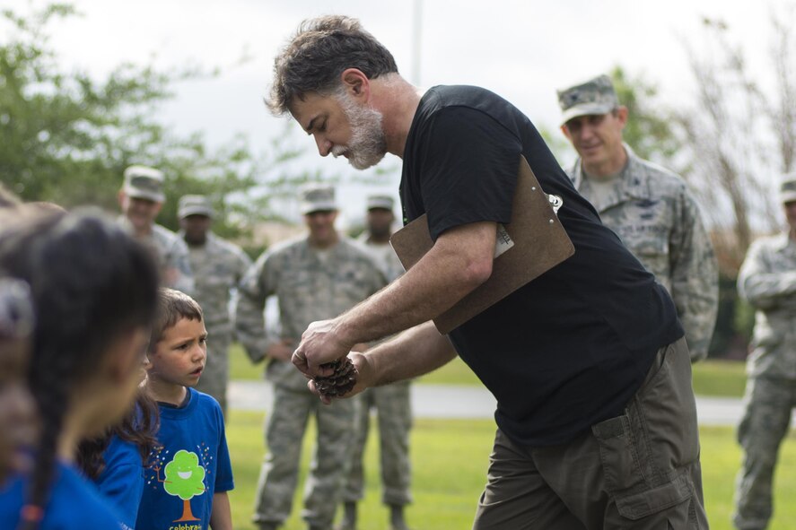 John Crain, 23d Civil Engineer Squadron forester, shows children from the Child Development Center II a pinecone during an Arbor Day ceremony, April 28, 2016, at Moody Air Force Base, Ga. Crain taught children that trees contribute to all sorts of household items, to include toothpaste. (U.S. Air Force photo by Airman Daniel Snider/Released)