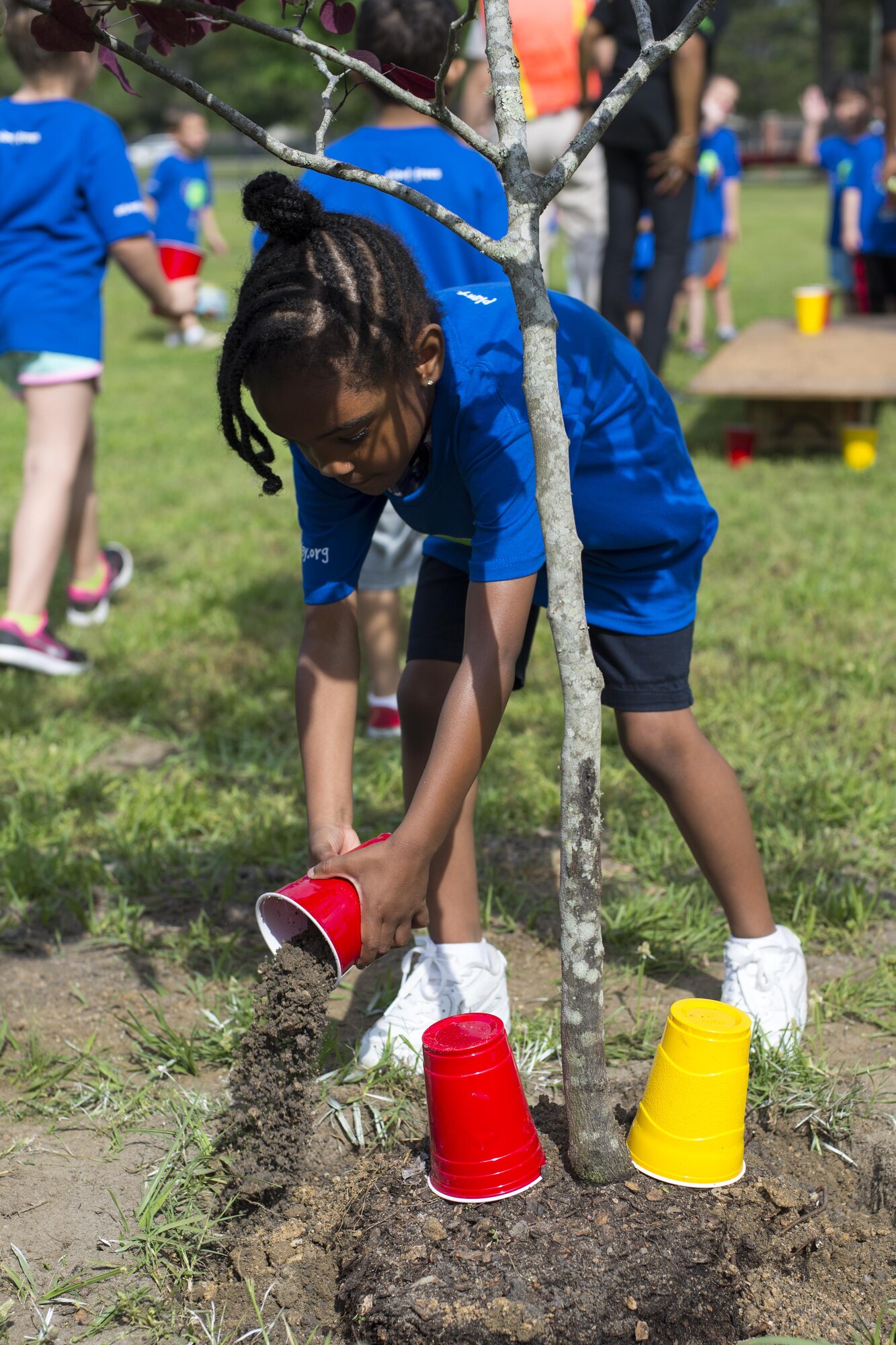 A child from the Child Development Center II pours soil into a hole to help to plant a tree during an Arbor Day ceremony, April 28, 2016, at Moody Air Force Base, Ga. The base forester and leadership teamed up to teach children the importance of trees and their effect on the environment. (U.S. Air Force photo by Airman Daniel Snider/Released)