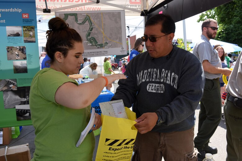 Zoe Roberts (Left), volunteer with the U.S. Army Corps of Engineers Nashville District, provides a goody bag with lake maps and water safety information to Murfreesboro resident John Cortez during Earth Day festivities in Town Square April 23, 2016. (USACE photo by Leon Roberts)