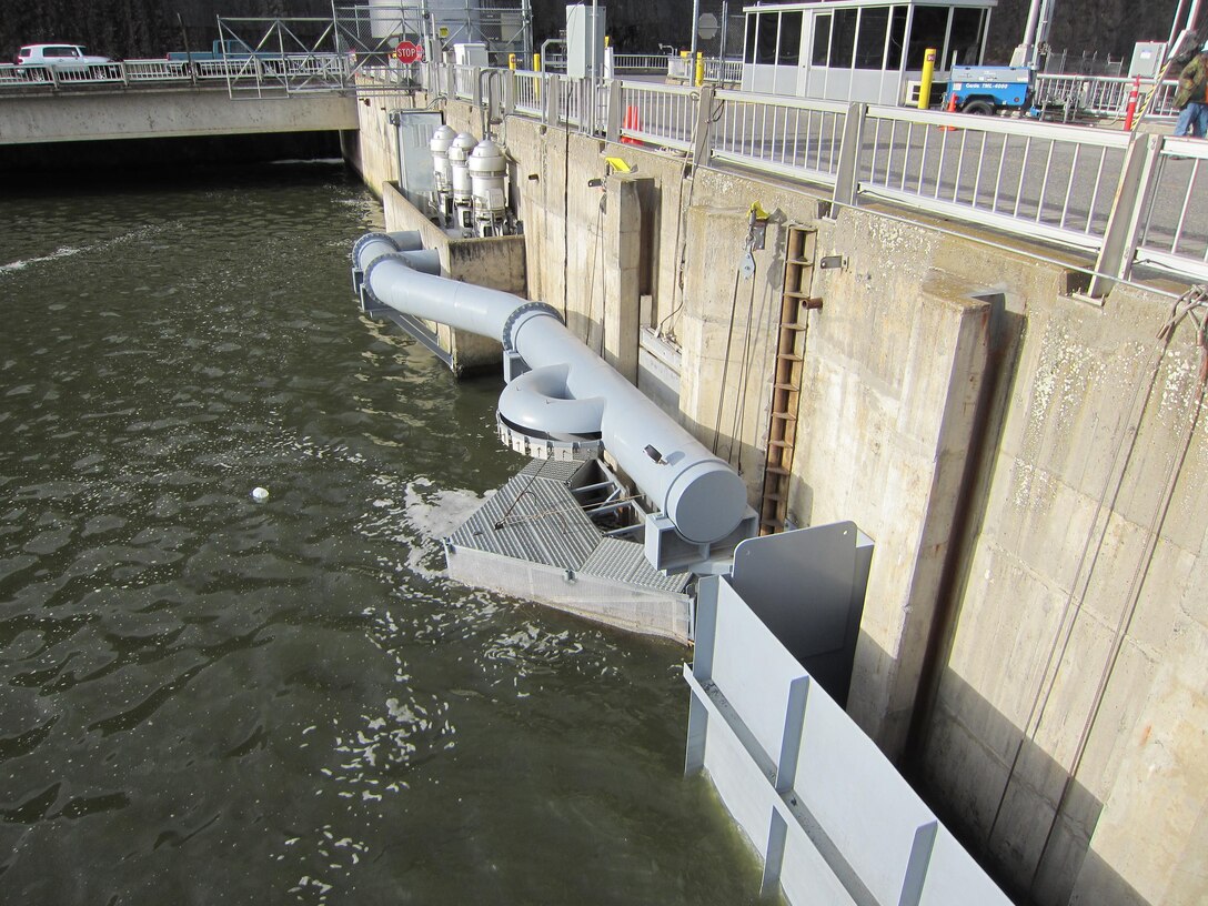 A pump extension intake chimney provides water to the upstream end of the adult fish ladder. The semi-circular pipe sprays water to cool the fish ladder and adjacent forebay area. 
