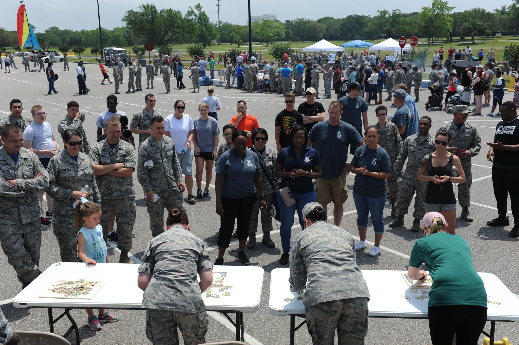 A crowd gathers to watch Airmen compete in the dragon puzzle competition during a burger burn April 29, 2016, Keesler Air Force Base, Miss. The burger burn was the final event of Wingman Week in support of Comprehensive Airman Fitness. (U.S. Air Force photo by Kemberly Groue)