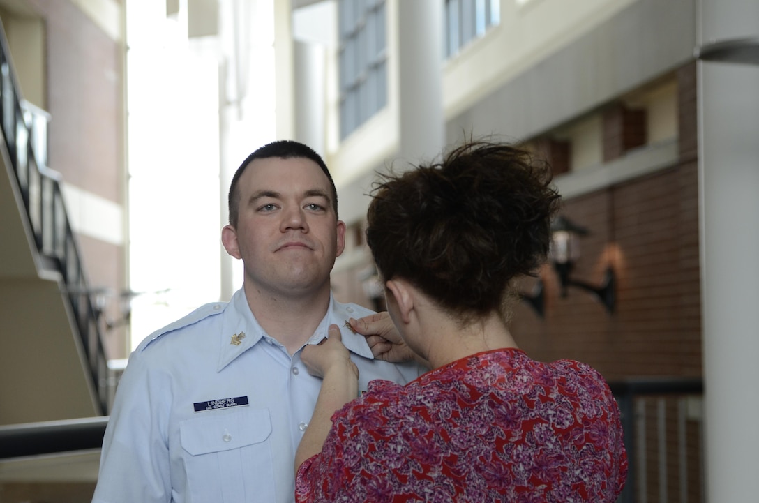 Coast Guard Petty Officer 1st Class Jonathan Lindberg stands at attention as his wife, Hollie Lindberg, pins on his new rank device during an April 1, 2016, ceremony at the Defense Information School on Fort Meade, Md. Lindberg graduated from DINFOS in 2008 and returned as an instructor in 2014.