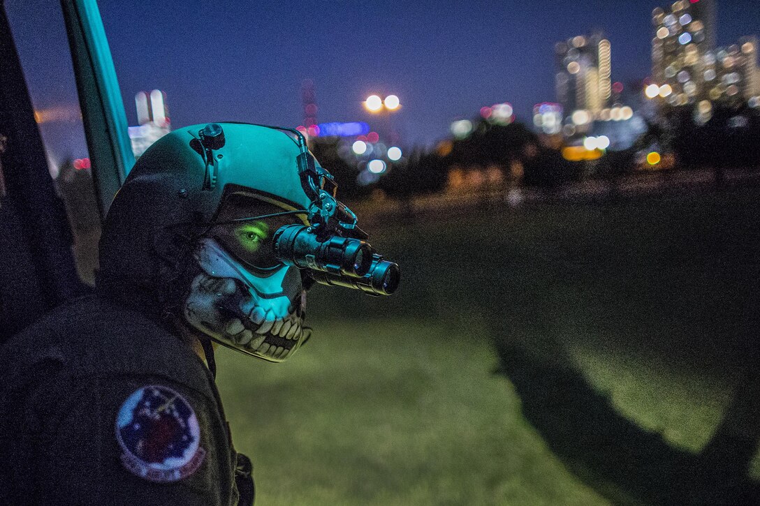 Air Force Tech. Sgt. Christopher Rector performs a visual conformation using night vision goggles during a training flight over U.S. Army Garrison Yokohama North Dock, Japan, April 25, 2016. Rector is a UH-1N Iroquois special missions aviator evaluator assigned to the 459th Airlift Squadron, which frequently trains to stay prepared for potential real-world contingencies and operations. Air Force photo by Yasuo Osakabe