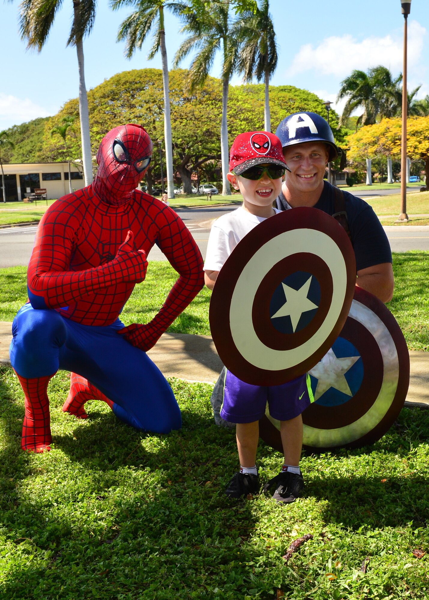 SSgt. Christopher Stoltz, Joint Base Pearl Harbor-Hickam Public Affairs, dressed as Spiderman, and Tech. Sgt. Brandon Hockenbarger, 15th Medical Group, dressed as Captain America, takes a photo with Xander Engle during the Books on Bases event on Joint Base Pearl Harbor-Hickam, April 28, 2016.  In celebration of the Month of the Military Child, the 15th Wing Public Affairs office and JBPHH Public Affairs office teamed up with Blue Star Families to provide more than 1,000 books to children of servicemembers. The free event, which also offered attendees an opportunity to take pictures with a few of their favorite super heroes, also doubled as a food drive. More than 300 pounds of canned good items were collected to donate to local food banks. (U.S. Air Force Photo by Tech. Sgt. Aaron Oelrich/Released)