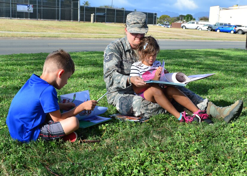 Staff Sgt. Katherine Danks reads to her daughter Charlotte as her Son Eddie reads his new book during the Books on Bases event on Joint Base Pearl Harbor-Hickam, April 28, 2016. In celebration of the Month of the Military Child, the 15th Wing Public Affairs office and JBPHH Public Affairs office teamed up with Blue Star Families to provide more than 1,000 books to children of servicemembers. The free event, which also offered attendees an opportunity to take pictures with a few of their favorite super heroes, also doubled as a food drive. More than 300 pounds of canned good items were collected to donate to local food banks. (U.S. Air Force Photo by Tech. Sgt. Aaron Oelrich/Released)