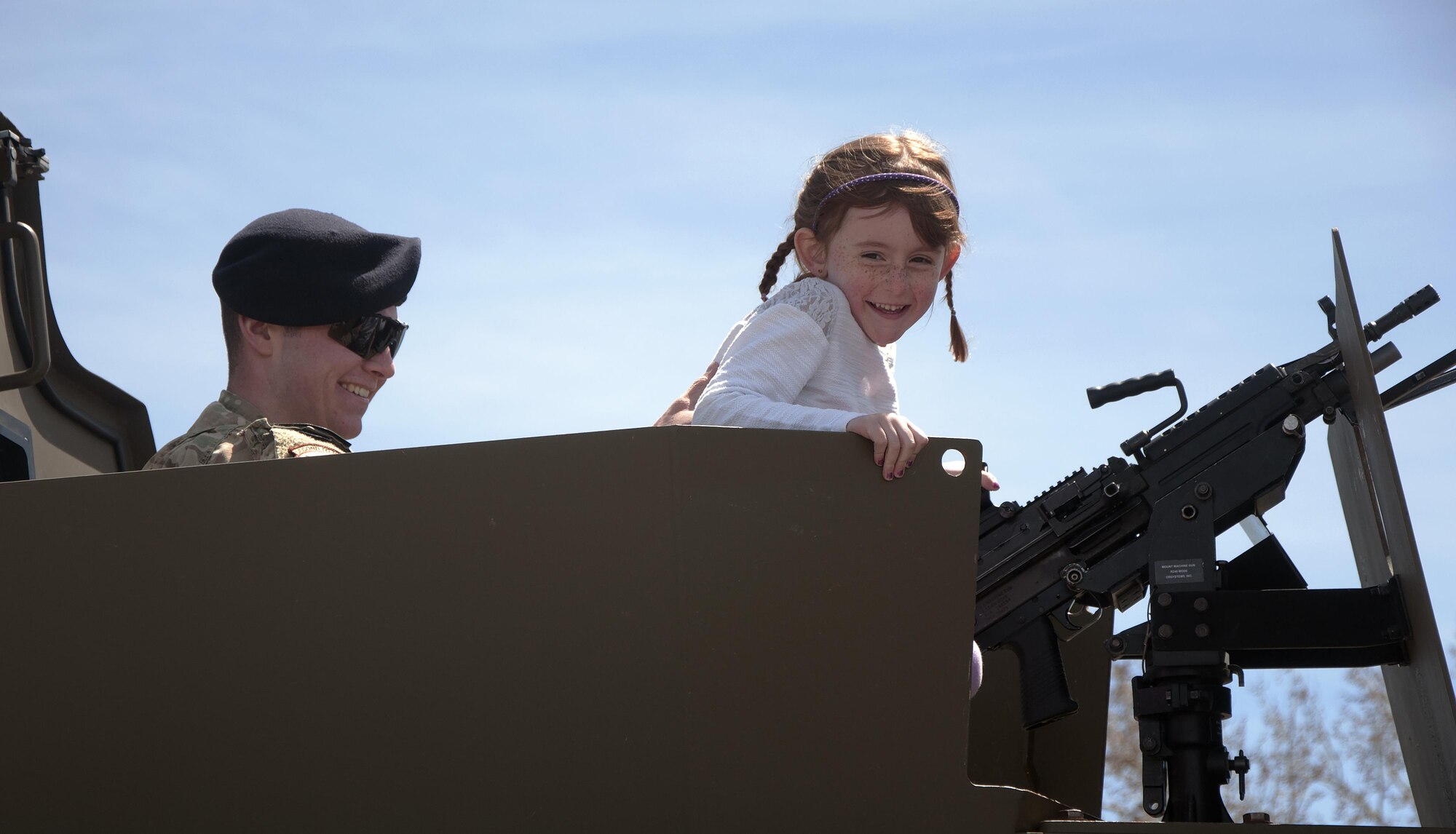 Airman 1st Class Dylan Bolger, 790th Missile Security Forces Squadron Security Support Team, helps Blaire Lycan, daughter of Capt. David Lycan, 90th Security Support Squadron, see the view from the gunner’s seat of a 90th Security Forces Group BearCat armored vehicle May 2, 2016, during a spouse’s appreciation week event at the Military Working Dogs facility. Spouses and children were able to check out the interior of security forces vehicles, see the equipment used by defenders, and get an up-close demonstration of the working dogs. (U.S. Air Force photo by Senior Airman Brandon Valle)