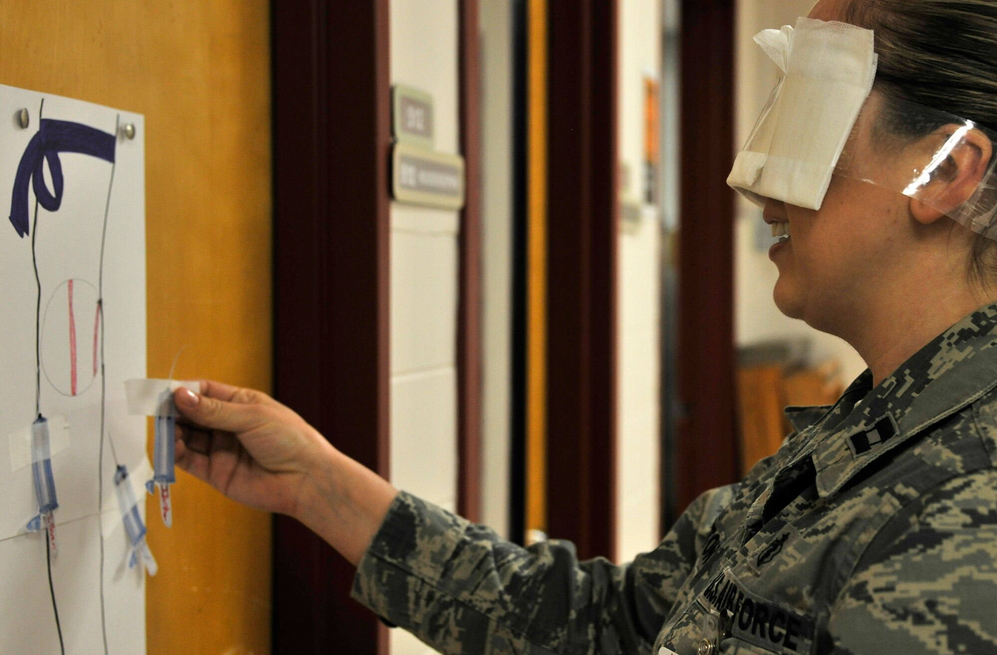 Capt. Cassie Johnston, 319th Medical Support Squadron chief laboratory services element, places a paper needle onto a drawn out patients arm during a game of “Pin the Needle in the Arm,” for the 2016 Medical Laboratory Professionals Week April 27, 2016, on Grand Forks Air Force Base, N.D. Laboratory professionals perform and supervise tests that lead to the detection of potential health problems; the sooner the disease is caught, the likelihood increases for a positive outcome. (U.S. Air Force photo by Senior Airman Xavier Navarro)