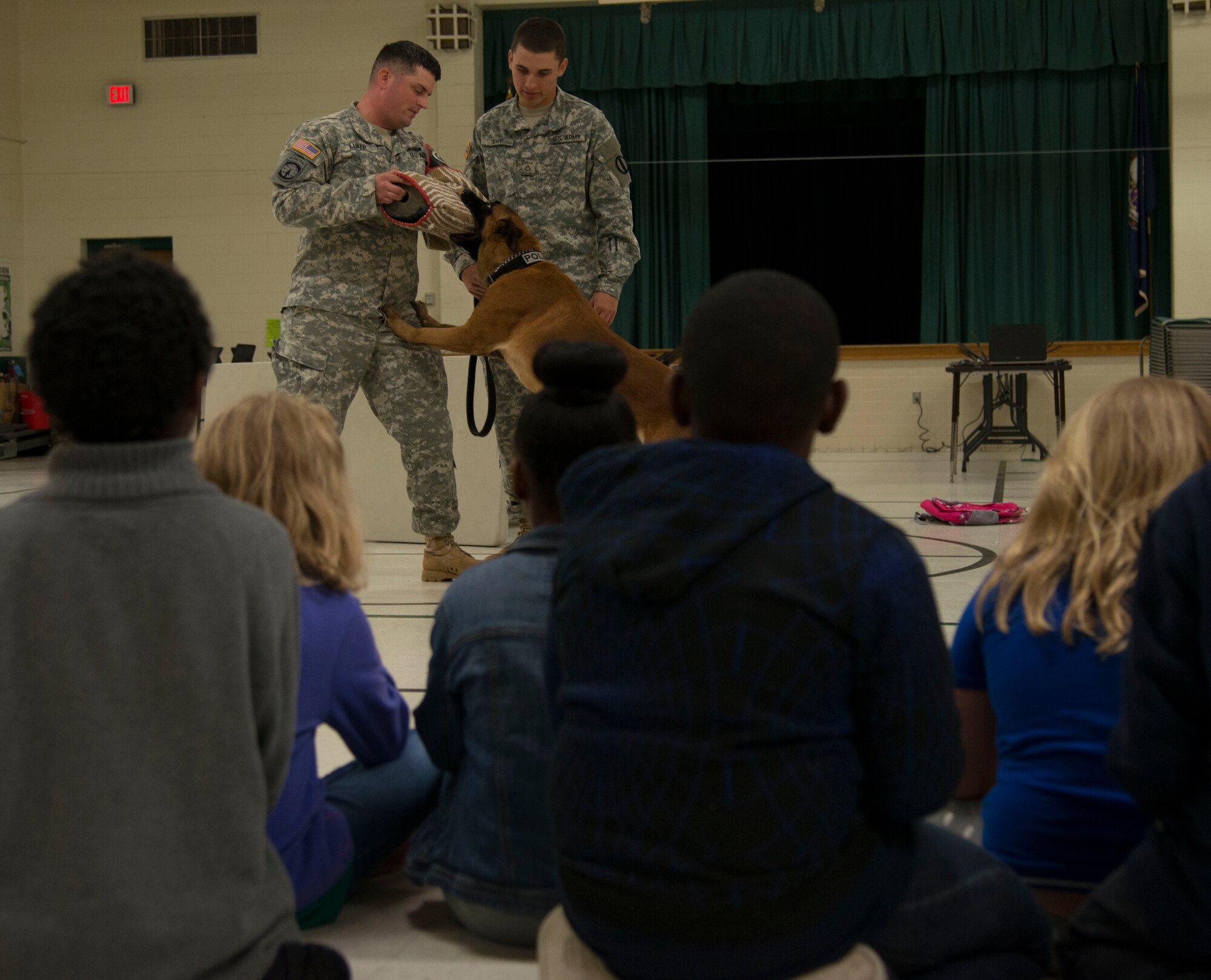 U.S. Army Sgt. Nathan Luker, left, and Pfc. Brendan Trapp, right, military working dog handlers from the 3rd Military Police Detachment K9, demonstrate an MWD’s capabilities during a career day at Richneck Elementary School in Newport News, Va., April 29, 2016. The purpose of this partnership building visit was to not only improve the community's understanding of the military, but to enhance the student's resiliency through safety demonstrations and tips.  (U.S. Air Force photo by Senior Airman Kristina LaCoste)