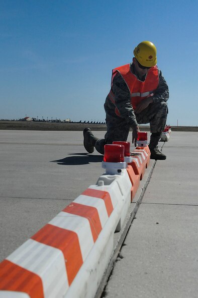 Airman 1st Class Benjamin Soto Garcia, airfield management operations coordinator assigned to the 5th Operations Support Squadron, inspects a light on a barricade located on taxiway delta and the associated hammerhead of Minot Air Force Base, N.D., April 13, 2016. Barricades are positioned to define the limits of hazardous areas, and lights are checked daily to ensure they are positioned and working properly. (U.S. Air Force photo/Airman 1st Class Jessica Weissman)