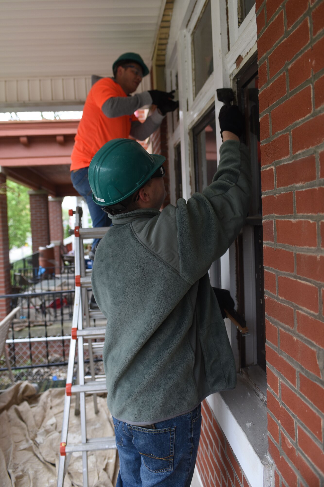 U.S. Air Force Tech. Sgt. Richard Green and Airman 1st Class Preston Reese, with the 121st Air Refueling Wing, chip away at old paint during a community outreach program with Habitat for Humanity April 23, 2016 Columbus, Ohio. EFAC Airmen helped to build a new walkway railing, repaint window sills and replace old windows for a local family in need. (U.S. Air National Guard photo by Airman 1st Class Ashley Williams/Released)