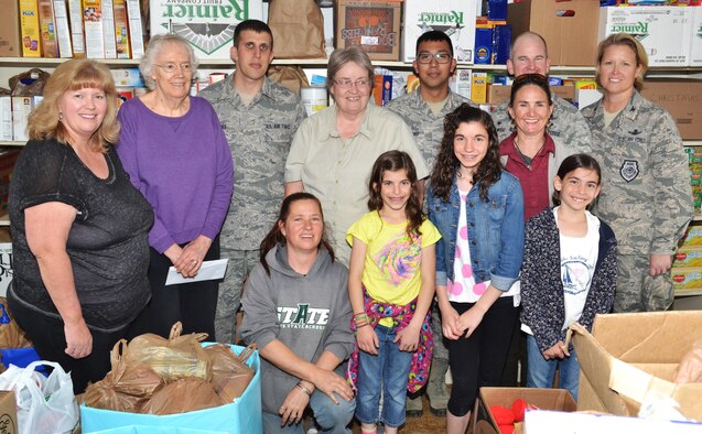 Col. DeAnna Burt, 50th Space Wing commander (right), stands in front of the fully stocked shelves at the Ellicott Helping Hands Food Pantry with pantry workers and volunteers from the Schriever Air Force Base Teens/Kids Helping Kids following a donation to the pantry in Ellicott, Colorado, Tuesday, April 26, 2016. The Teens/Kids Helping Kids group held a food drive at the Peterson Air Force Base commissary April 23-24 and raised more than $350 and collected 2,149 pounds of food for the pantry. (U.S. Air Force photo/Brian Hagberg)